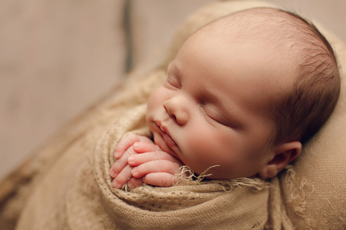 baby boy sleeping in blanket on neutral background
