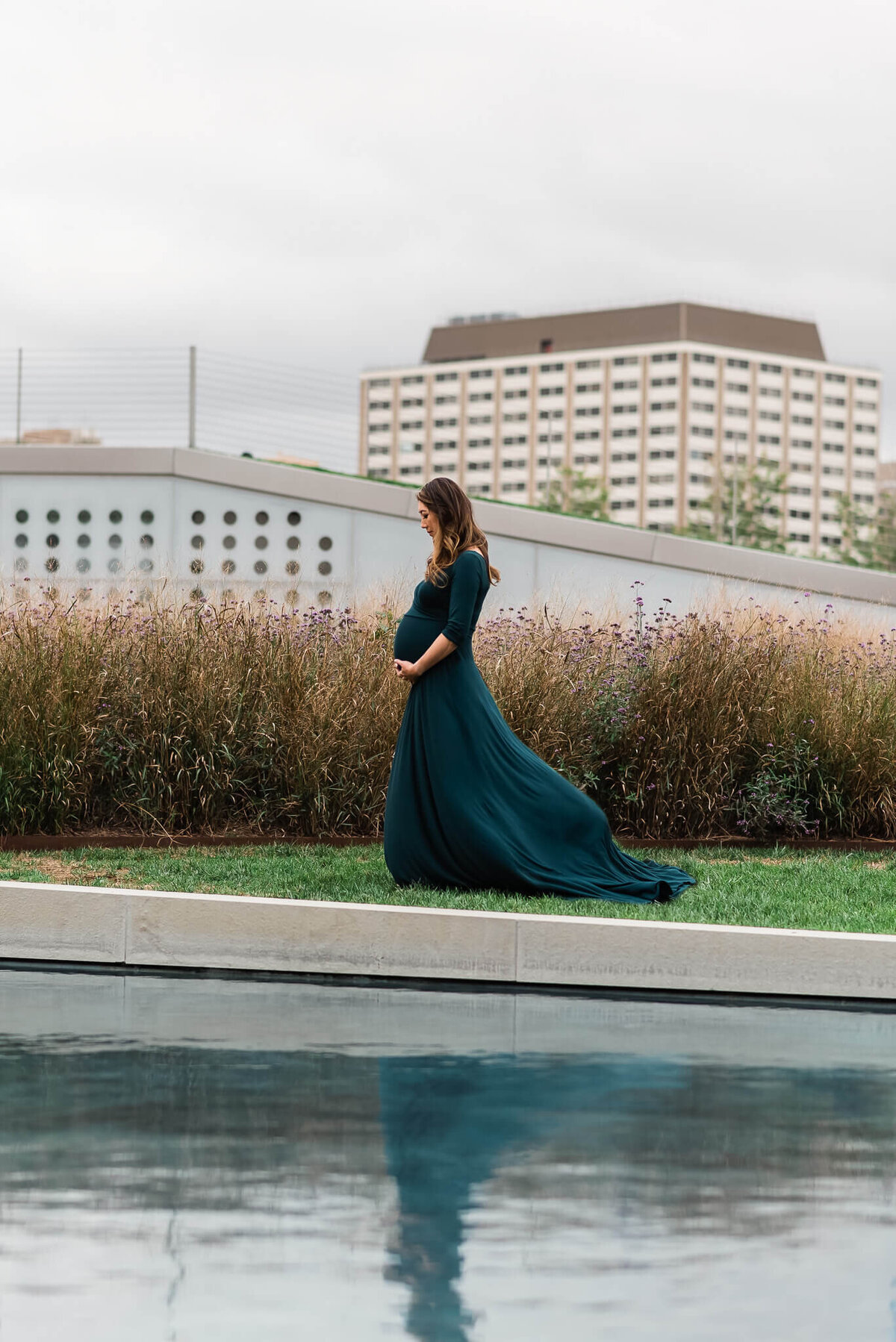 A reflection in the water of an expecting mother in a maternity gown by Denise Van Photography