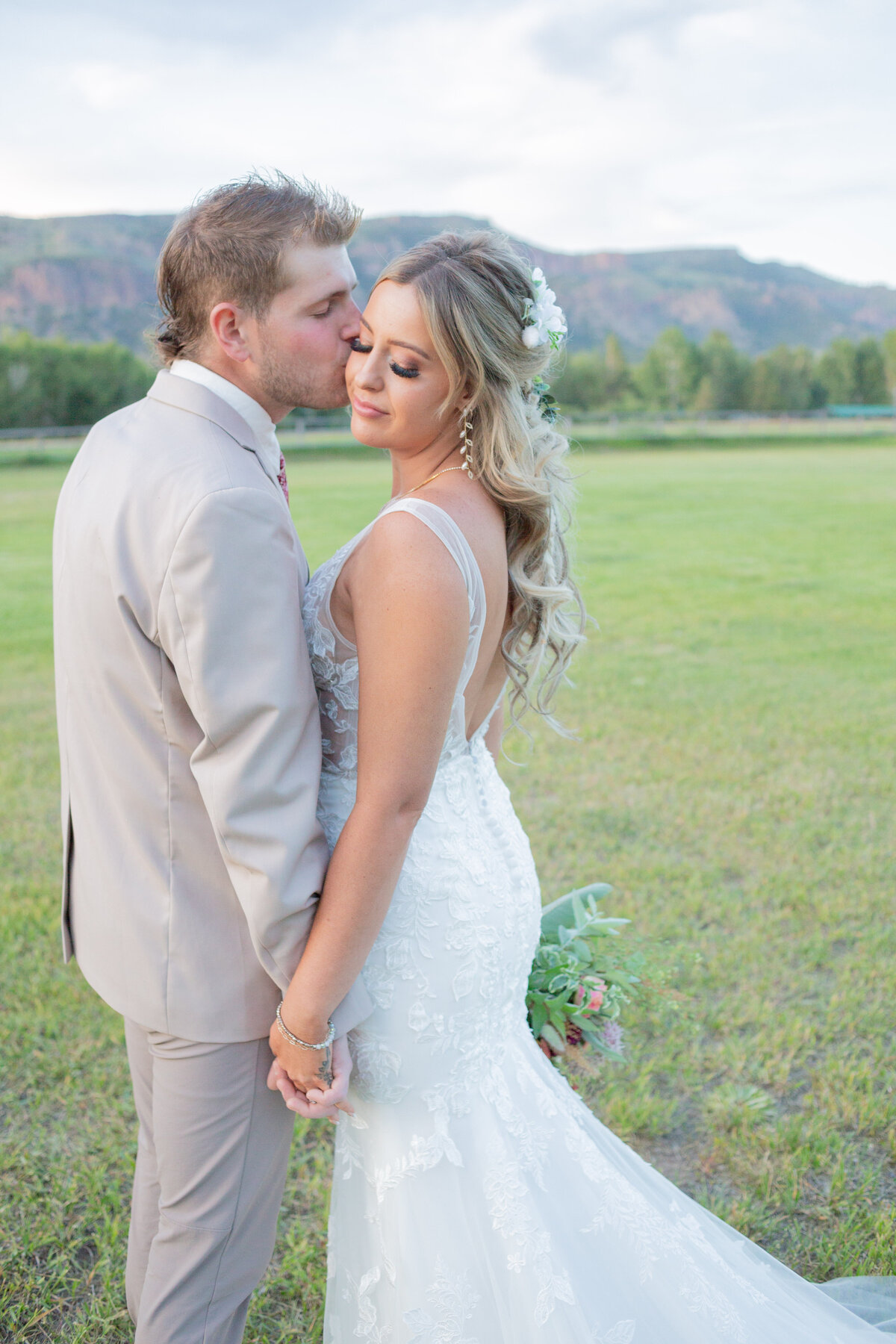 Washington Elopement Photographer captures groom kissing bride's cheek during outdoor bridal portraits after mountain elopement