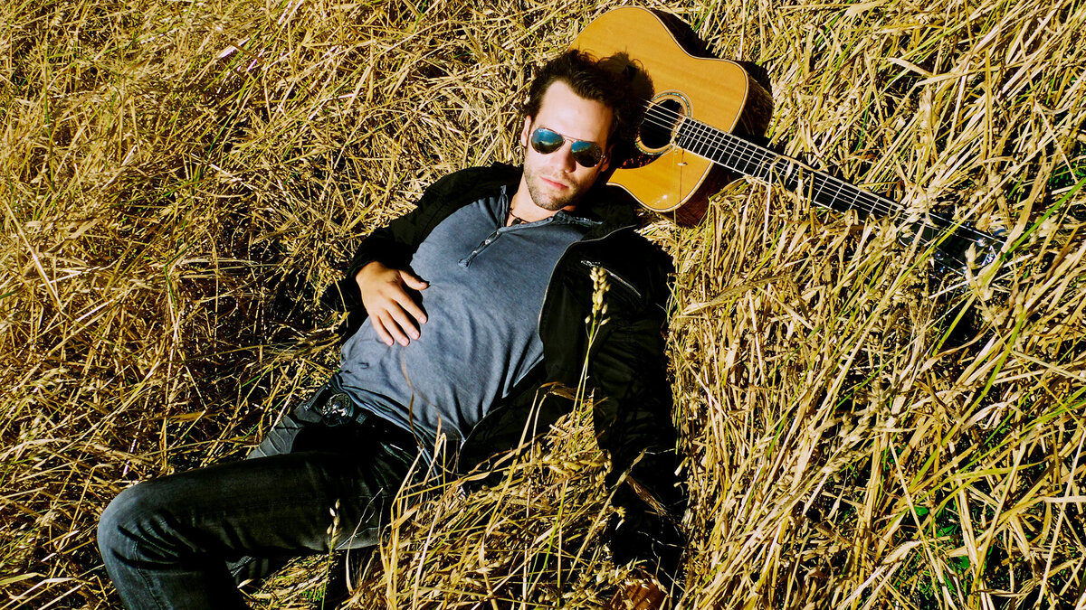 Country Music Artist photo  Chad Brownlee lying in grass field with guitar PEI