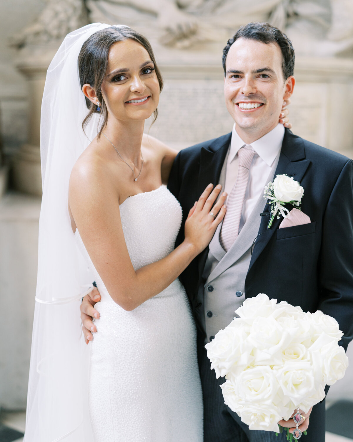 Bride and groom at traditional wedding in St Paul's Cathedral, with white rose bouquet