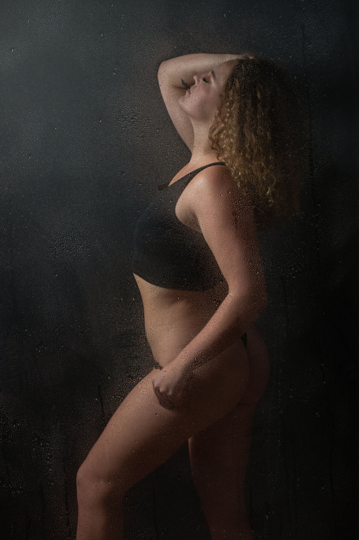 Woman wearing a black bathing suit standing in a shower for a boudoir shoot with Orlando boudoir photographer Khim Higgins.
