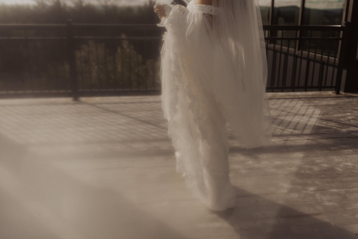 A bride on a balcony with flowing dress fabric and soft shadows.