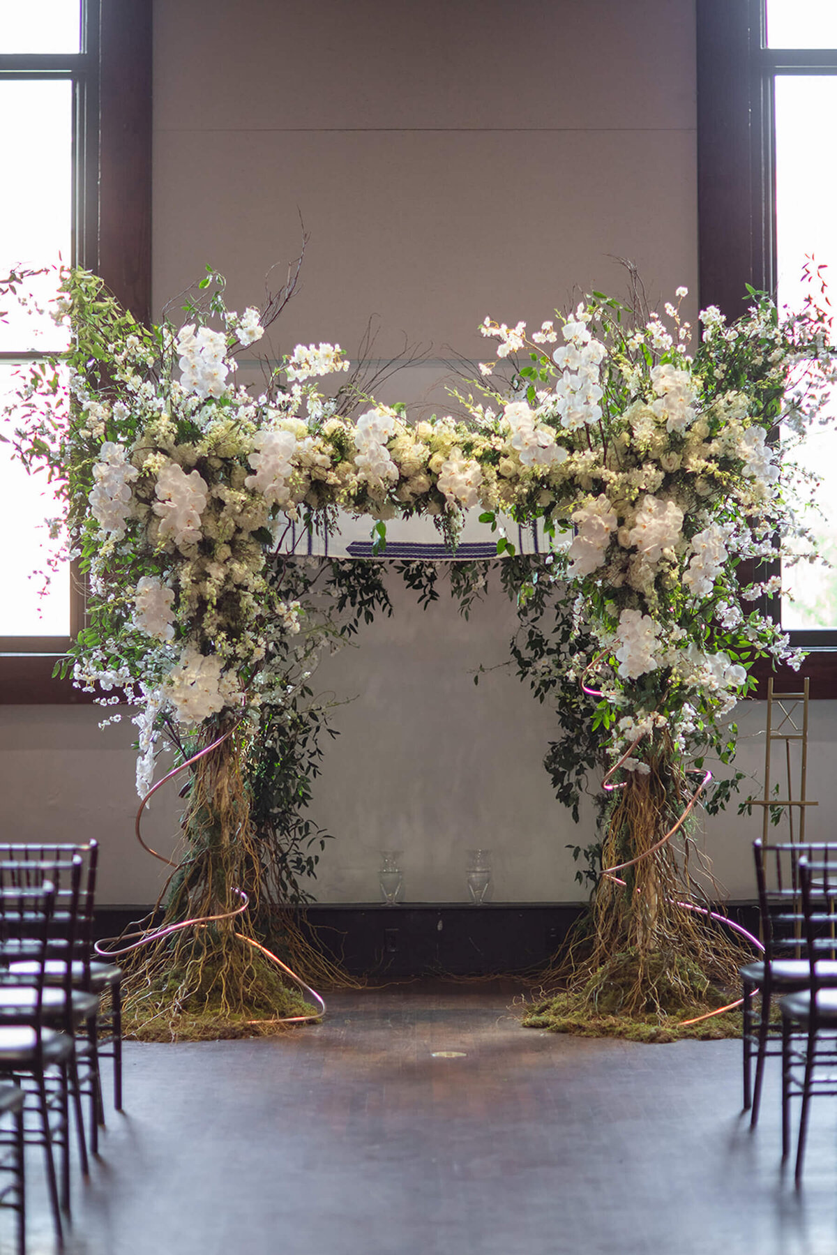 Floral covered chuppah with tree branch poles at Bell Towe