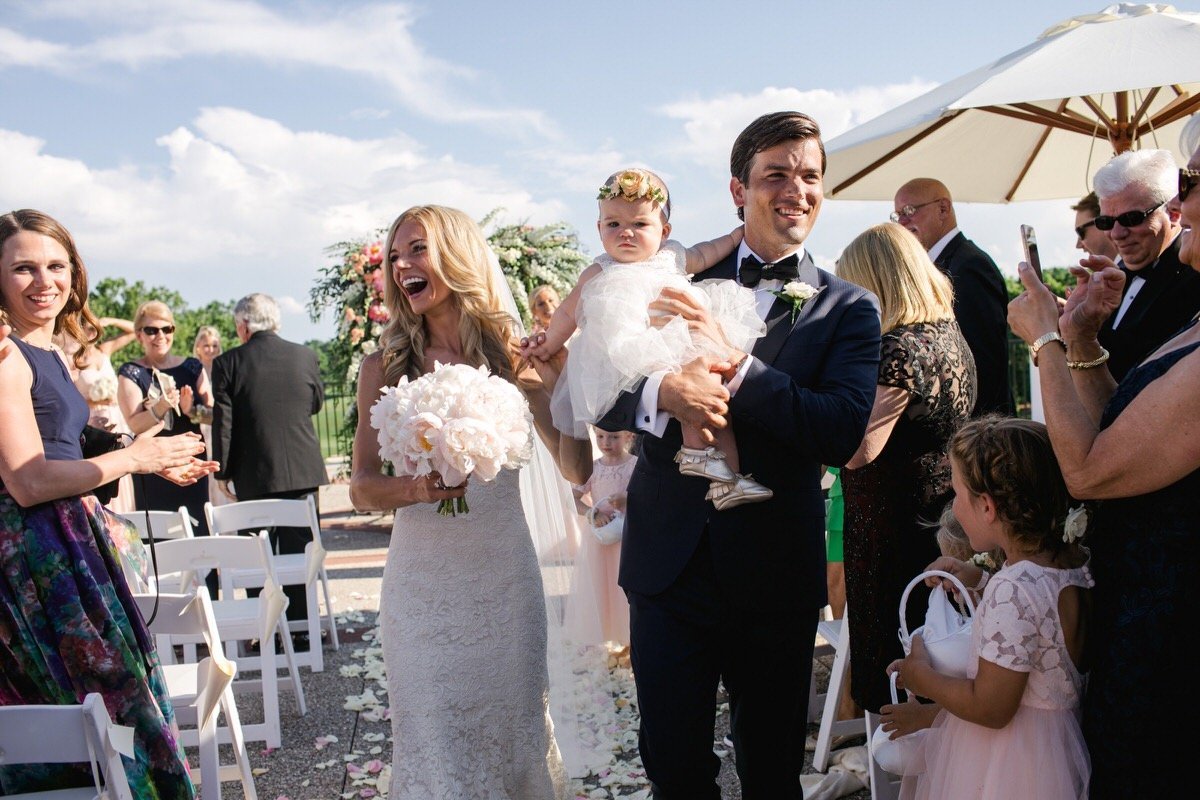 Bride and Groom walk down the aisle with their baby at the wedding