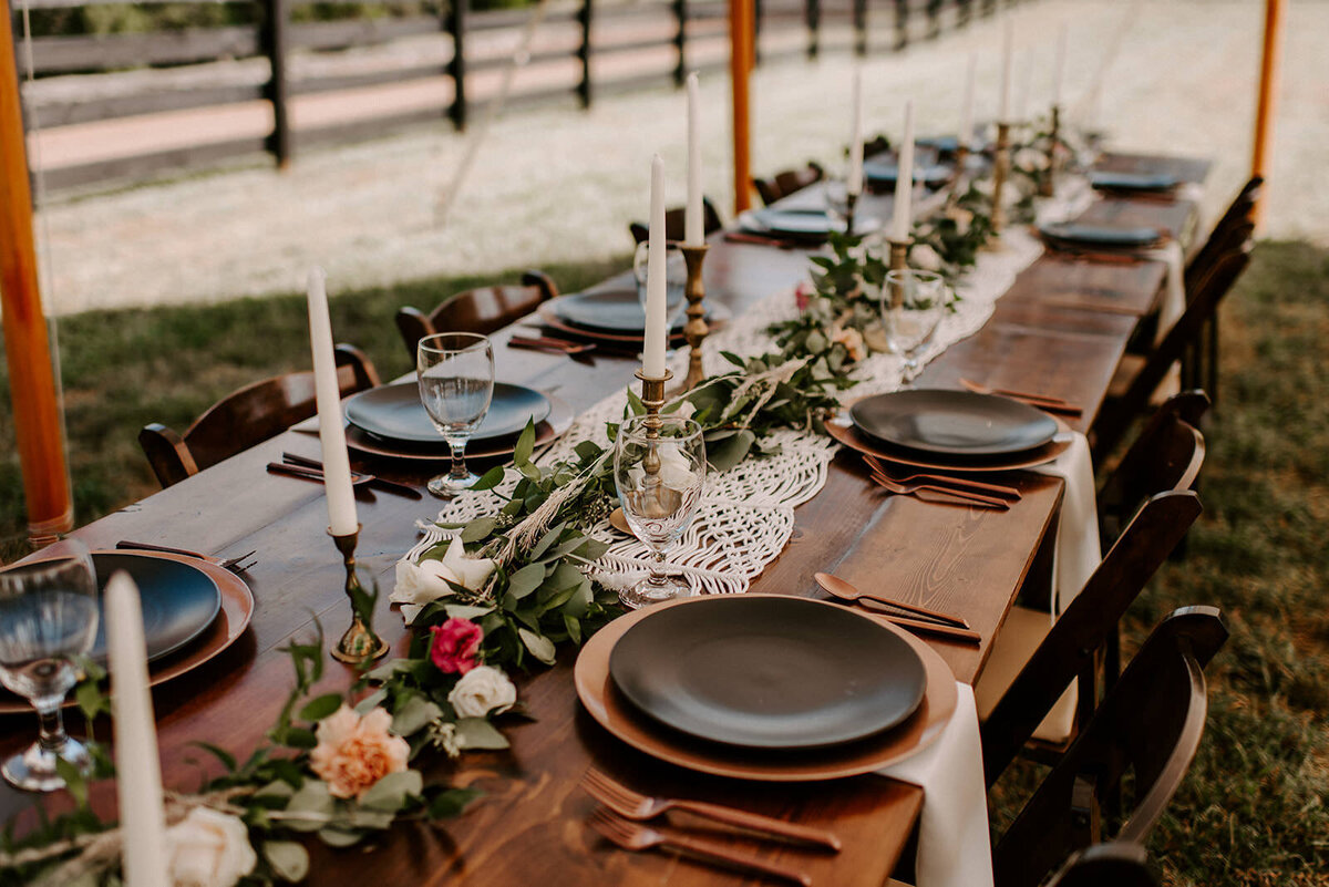 boho farm tables with black place settings, greenery with florals, and taper candles