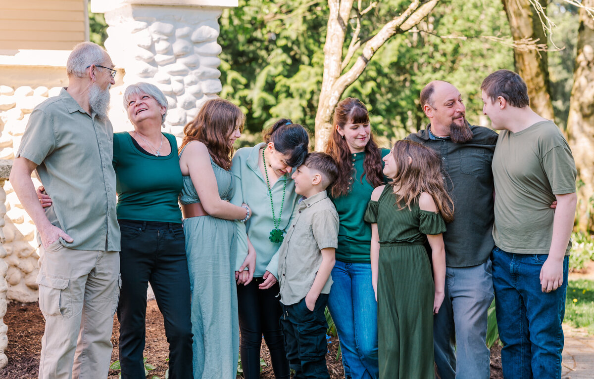 Extended family photos everyone smiling and chatting with each other. White building and greenery in the back round.