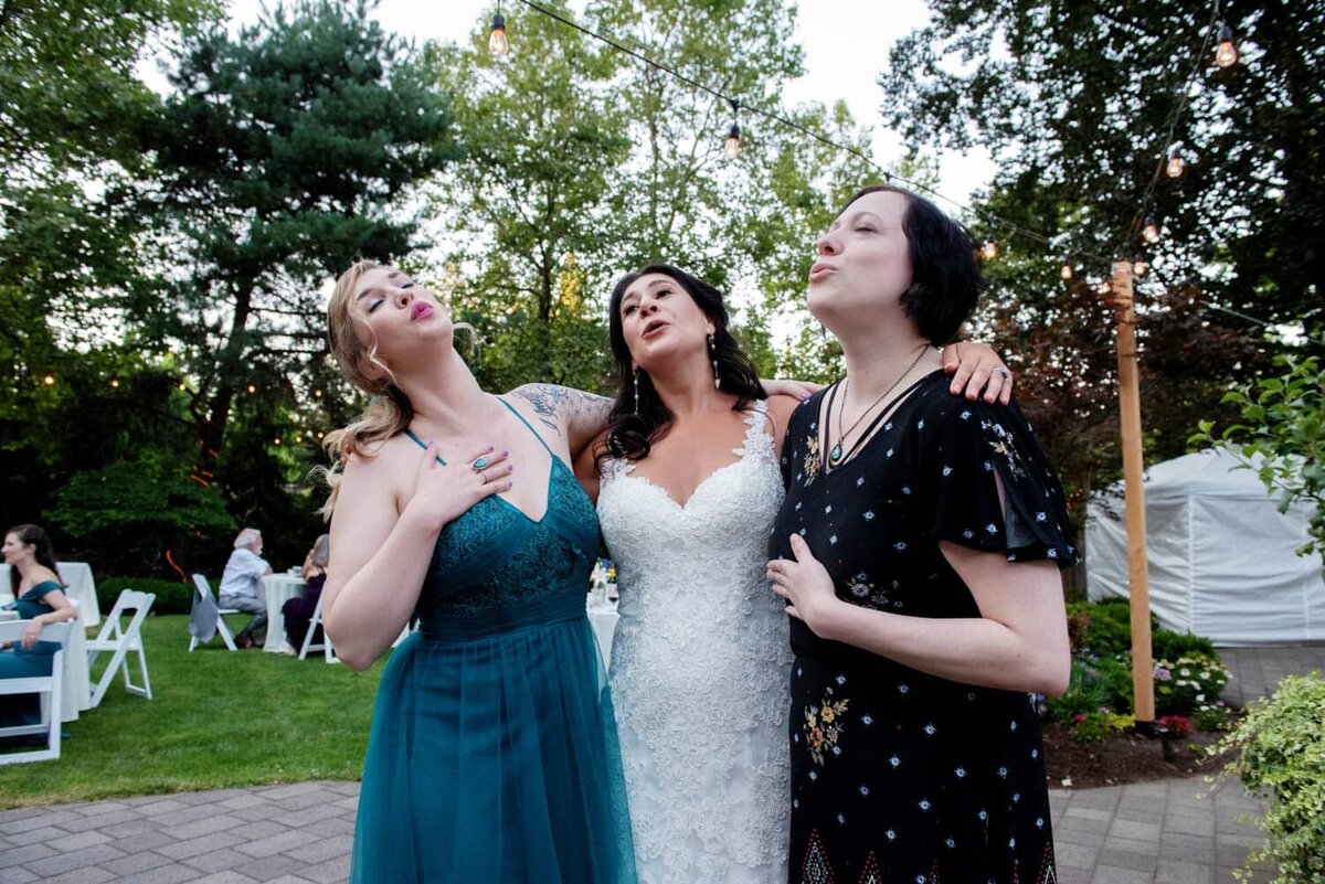 a bride and two friends hug and sign along to a Queen song