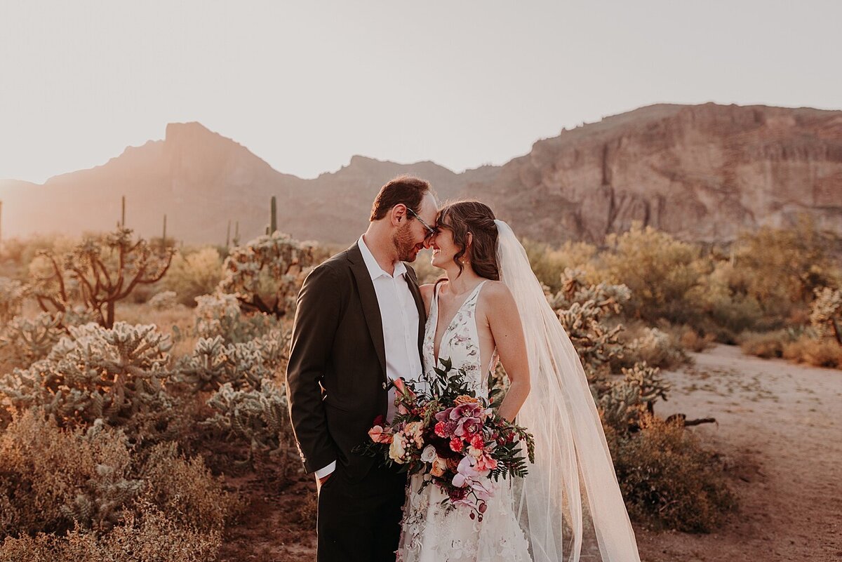 Wedding couple side hug holding flowers in the desert at sunset