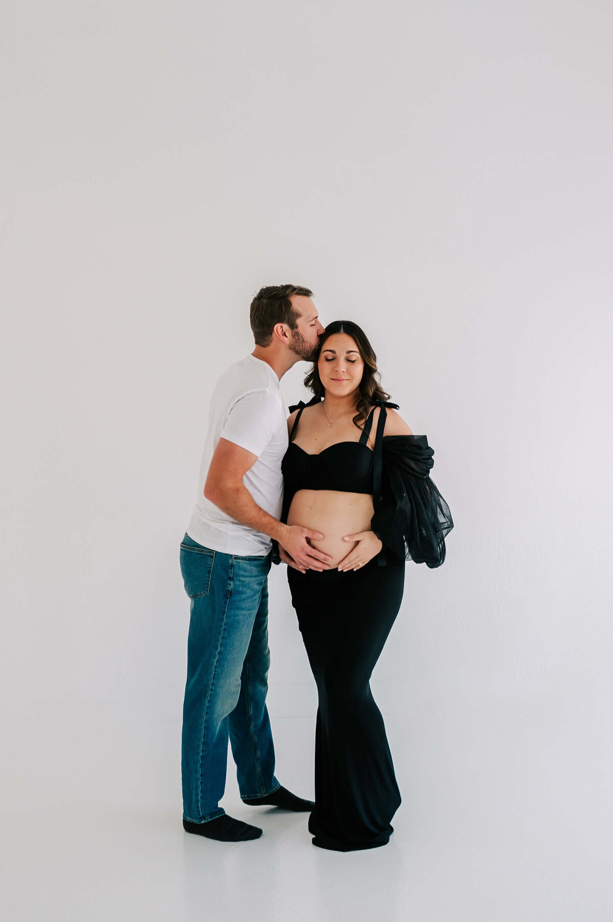 maternity photo of husband kissing wife's head holding baby bump during Springfield Mo maternity phogoraphy session