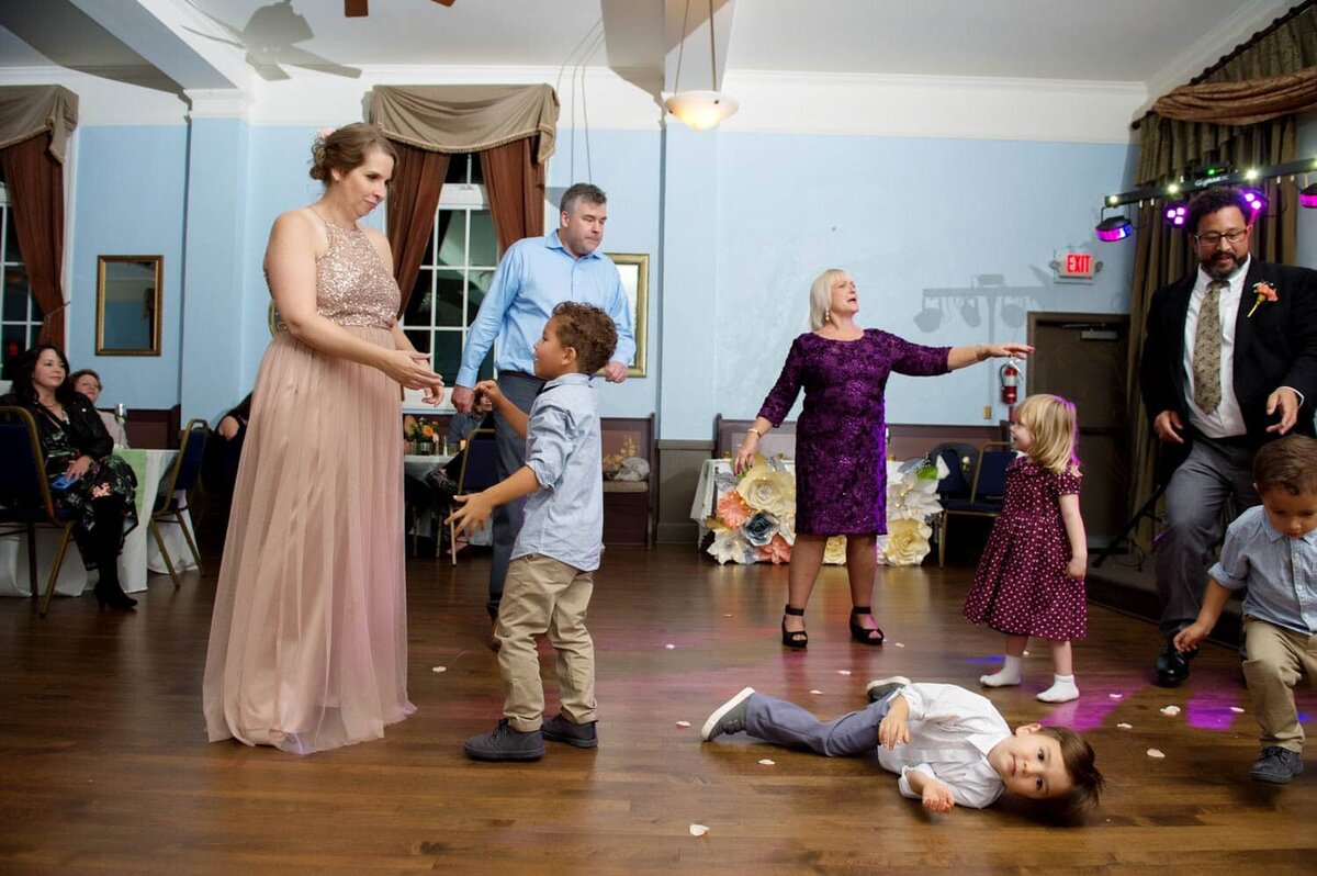 a child lays on the ground in the middle of a wedding reception dance floor