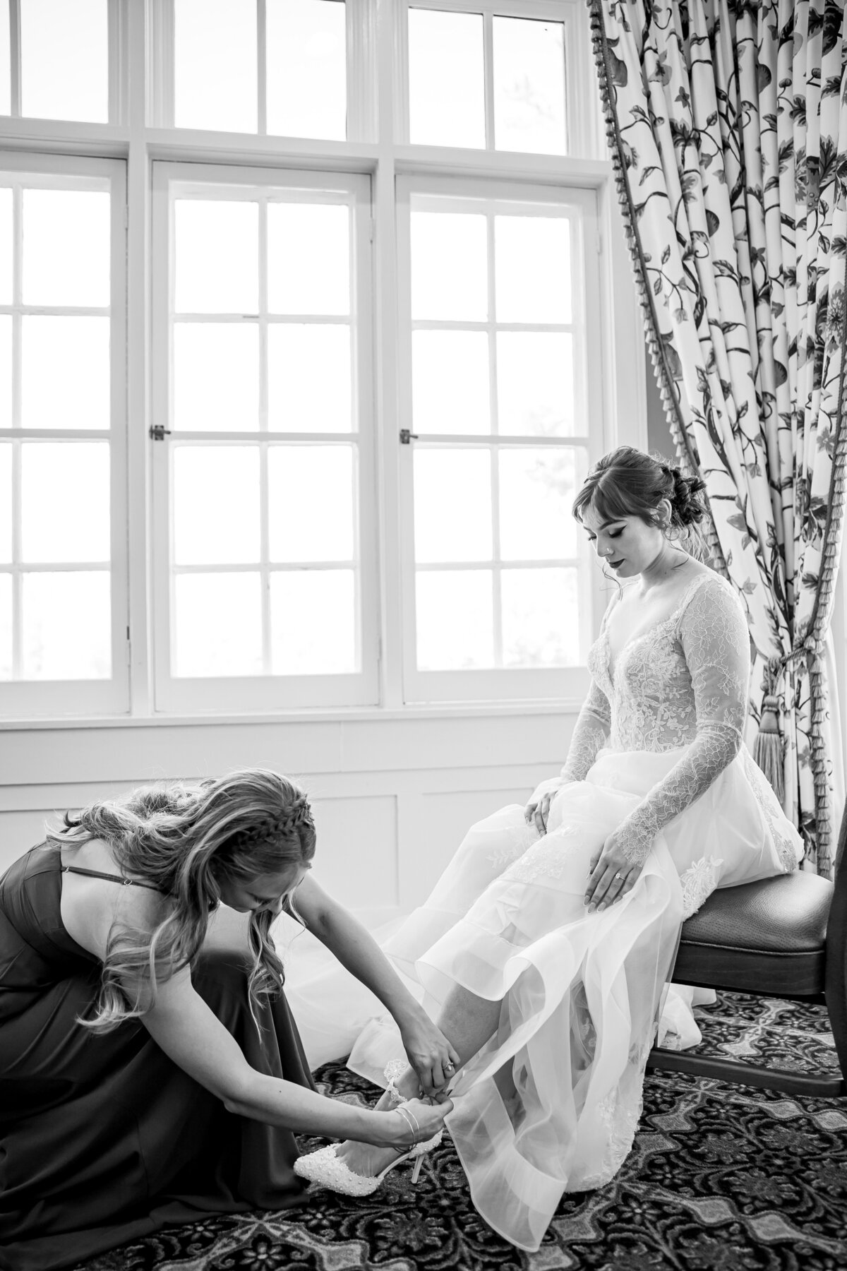 black and white photo of bride putting on shoes