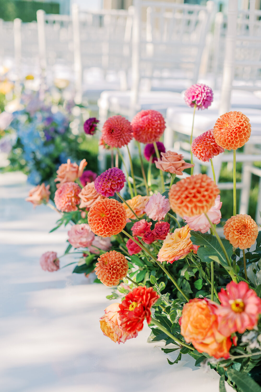 Bright orange, red and peach dahlias, roses and wedding aisle flowers