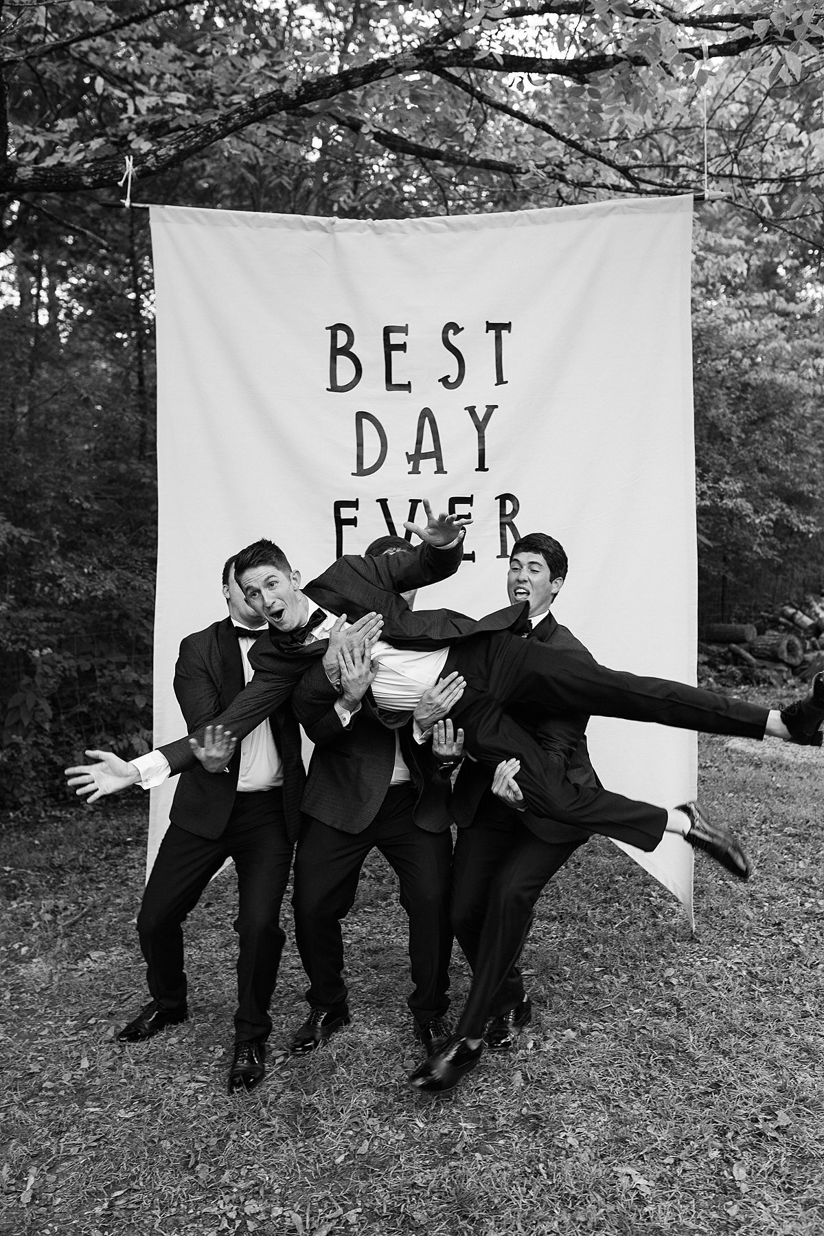 Disney Tangled themed wedding where groomsmen lift up groomsmen to toss him in the air in front of a Best Day Ever sign.