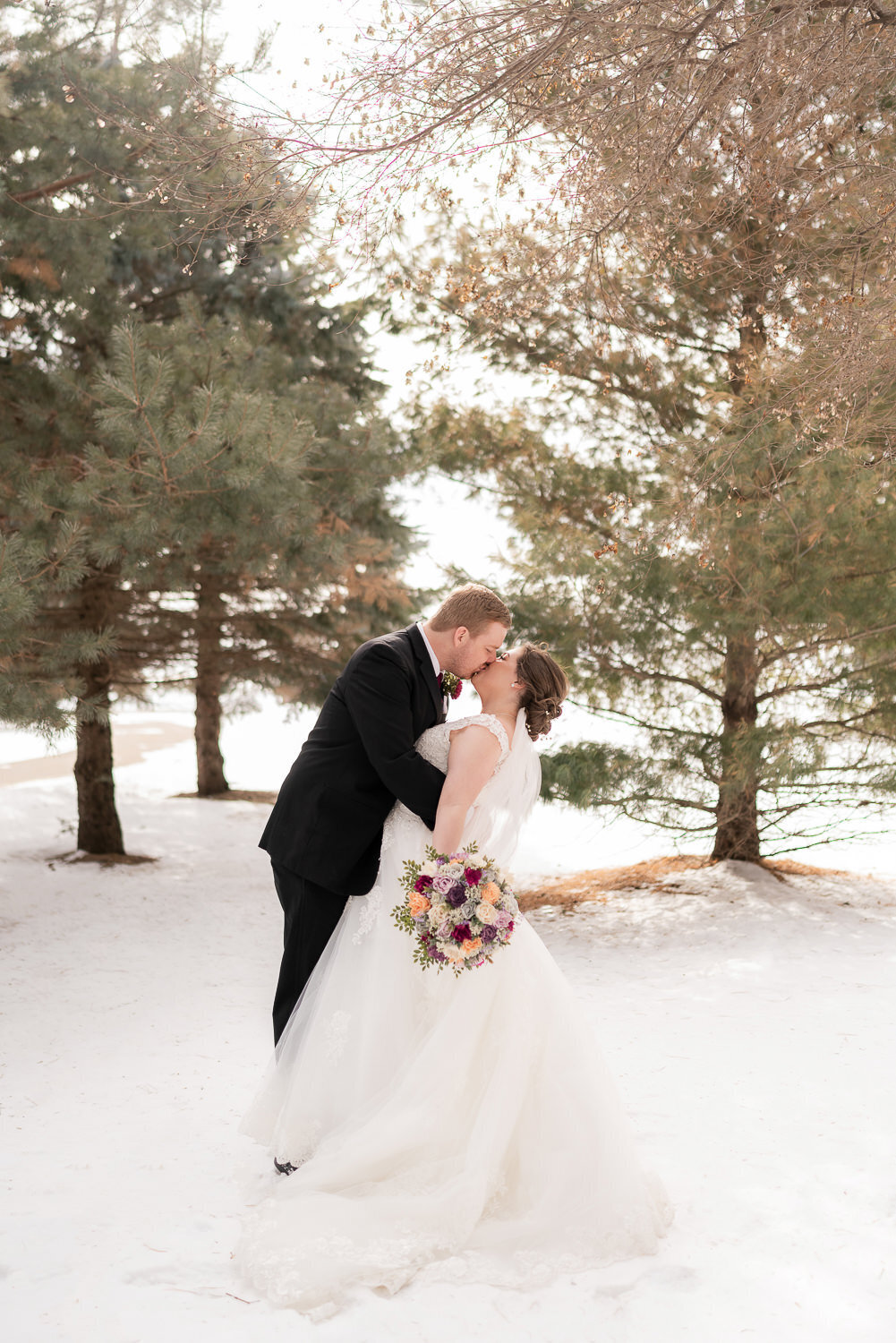 Bride and groom kiss in the snow in Farmington, Minnesota.