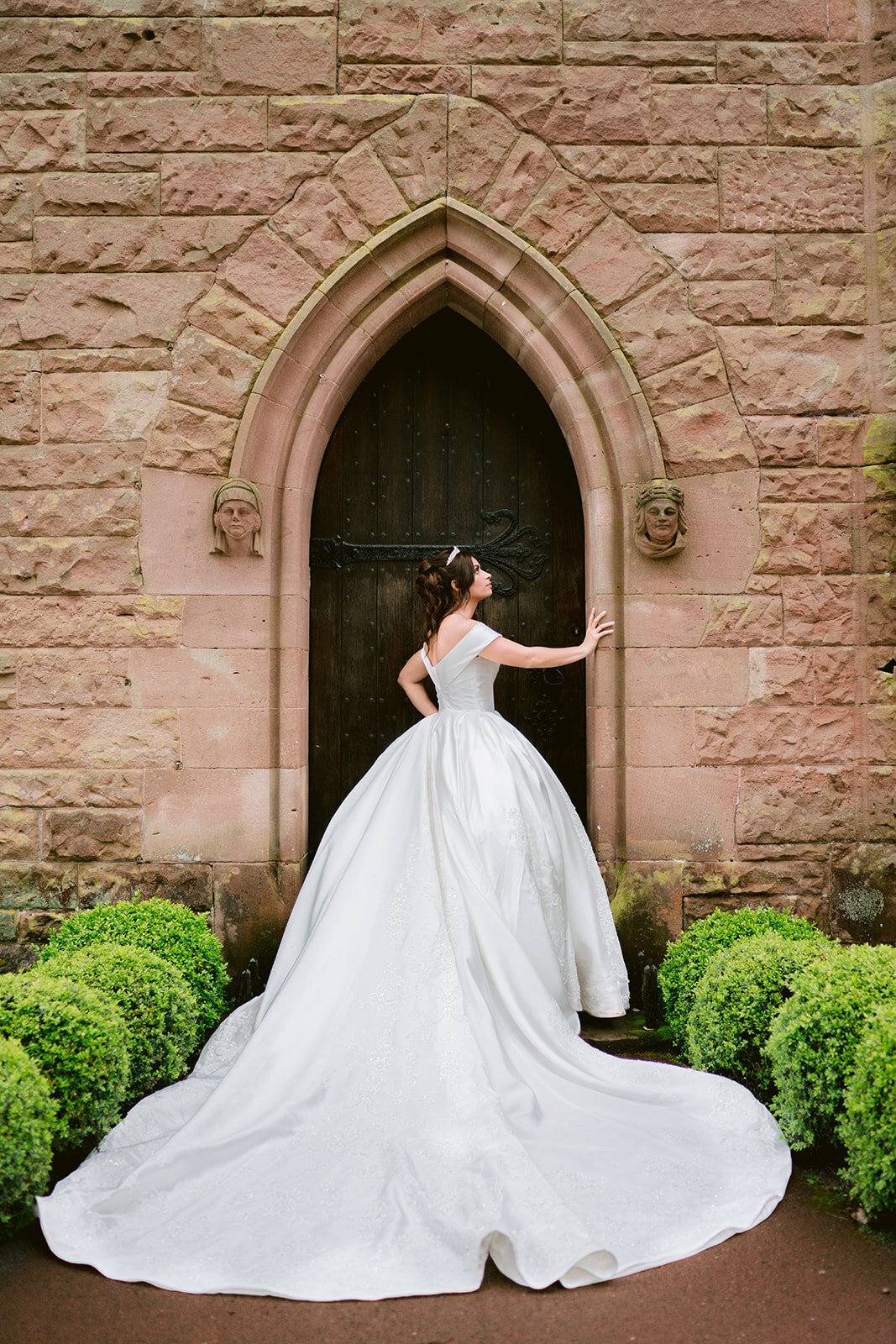 a bride in the doorway of the peckforton castle wedding chapel