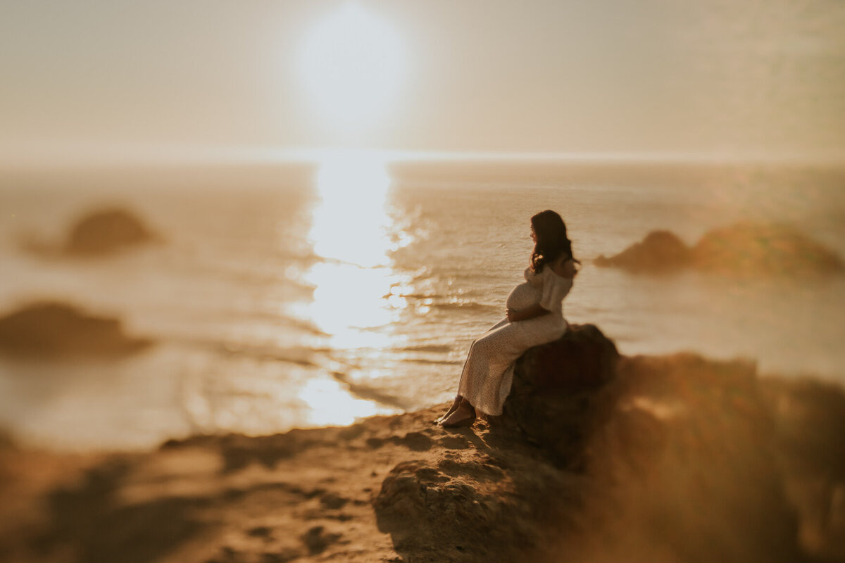 San Francisco maternity photo at Lands End.  Pregnant mom gazes at ocean and is bathed in light.