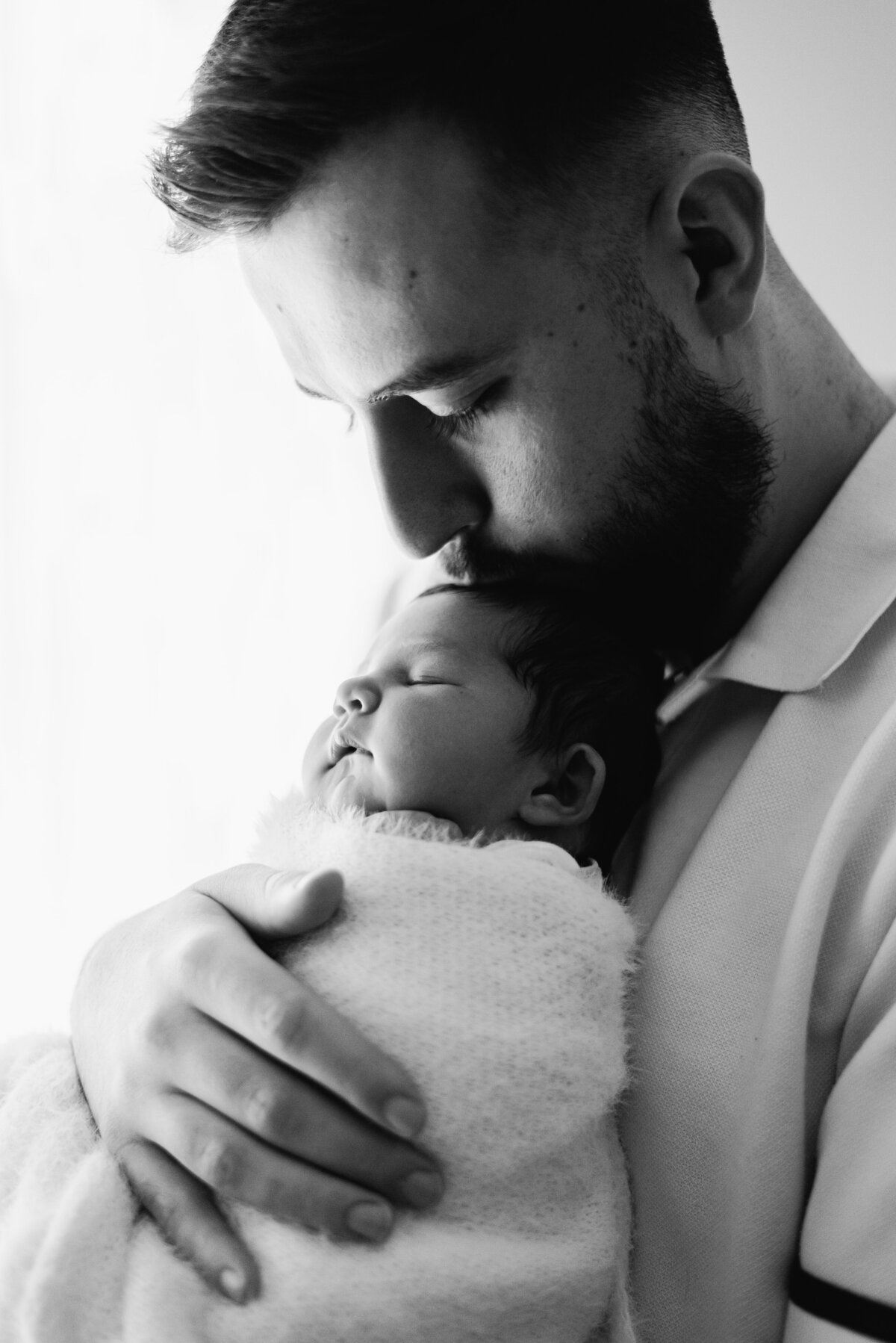 Man kissing his baby on her head at Billingshurst newborn photoshoot