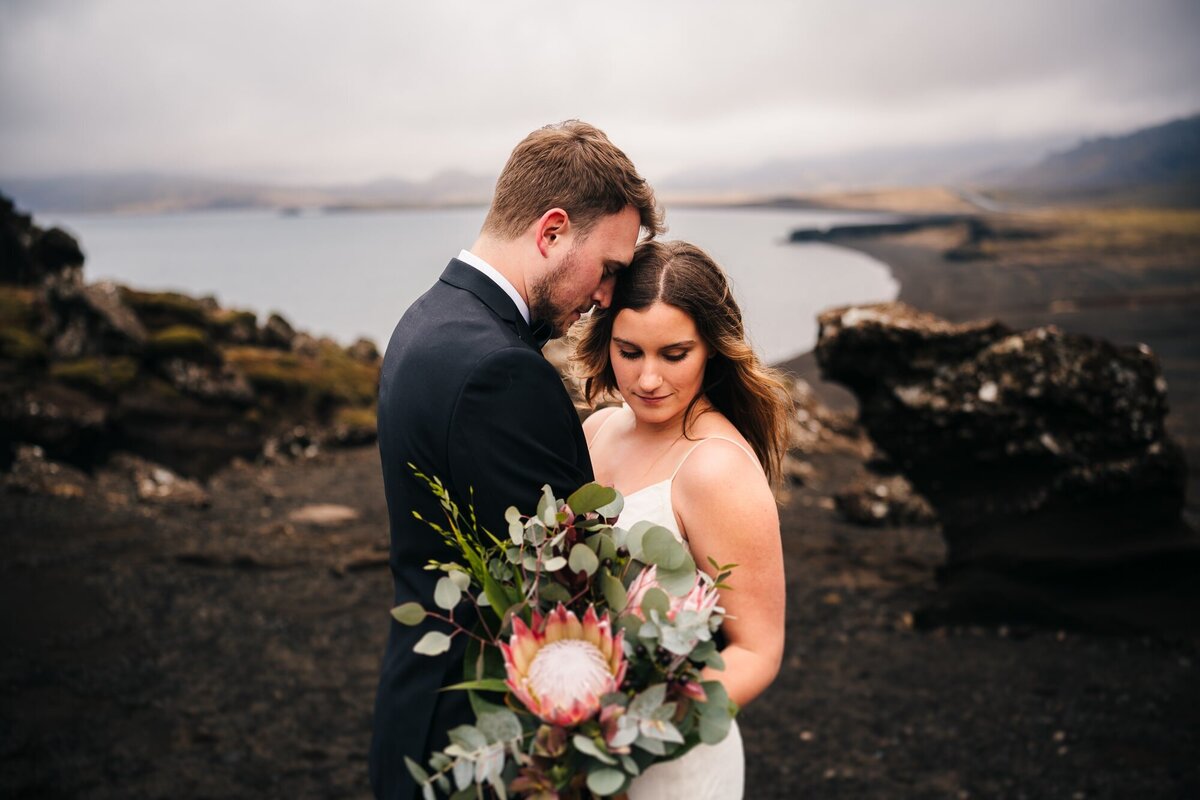 Embraced by love on the Icelandic coast, this couple faces each other snugly, surrounded by the breathtaking beauty of the coastal backdrop.