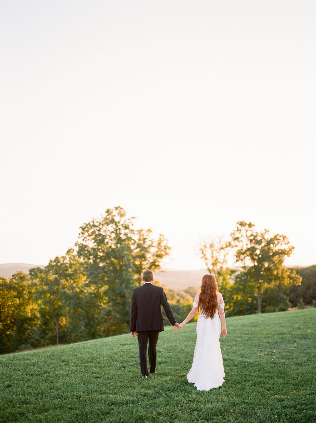 bride and groom holding hands in grassy field on philadelphia wedding day