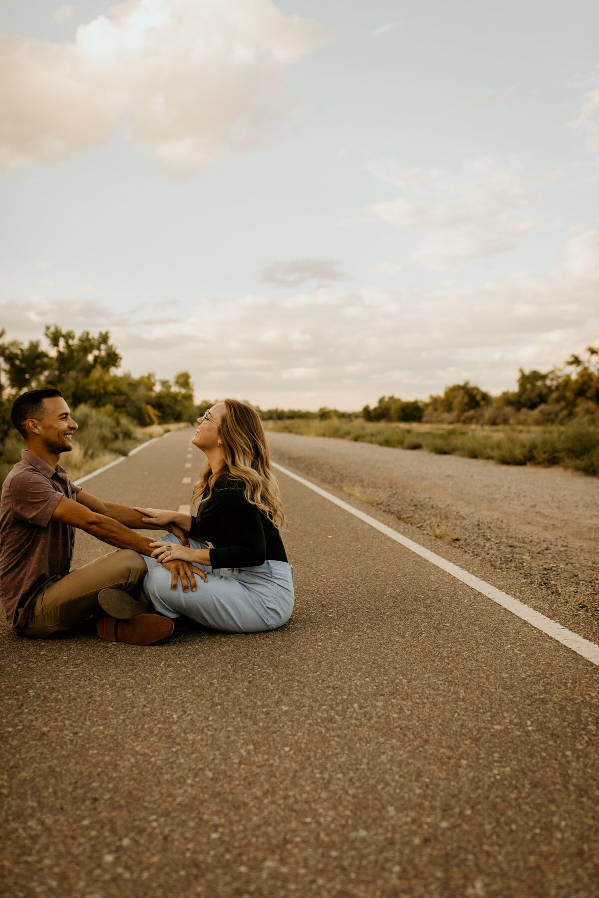 engaged couple sitting on a bike trail in Albuquerque laughing