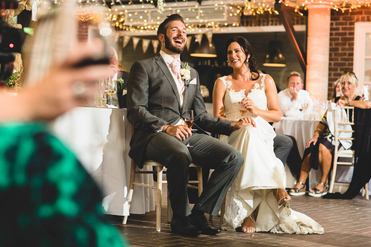 photo of a bride and groom laughing in the courtyard in the speeches at delamere manor