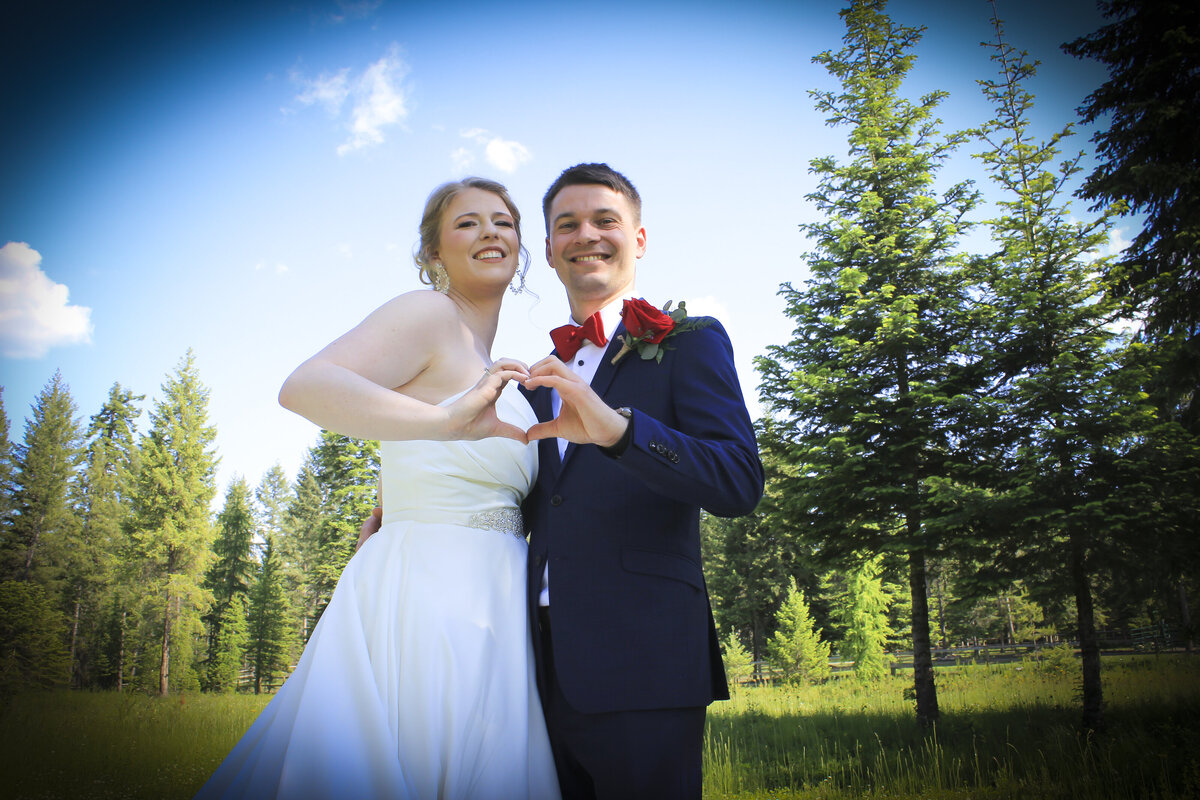 photo of a Bride and groom in a meadow with pine trees  on a summers day in bayview Idaho