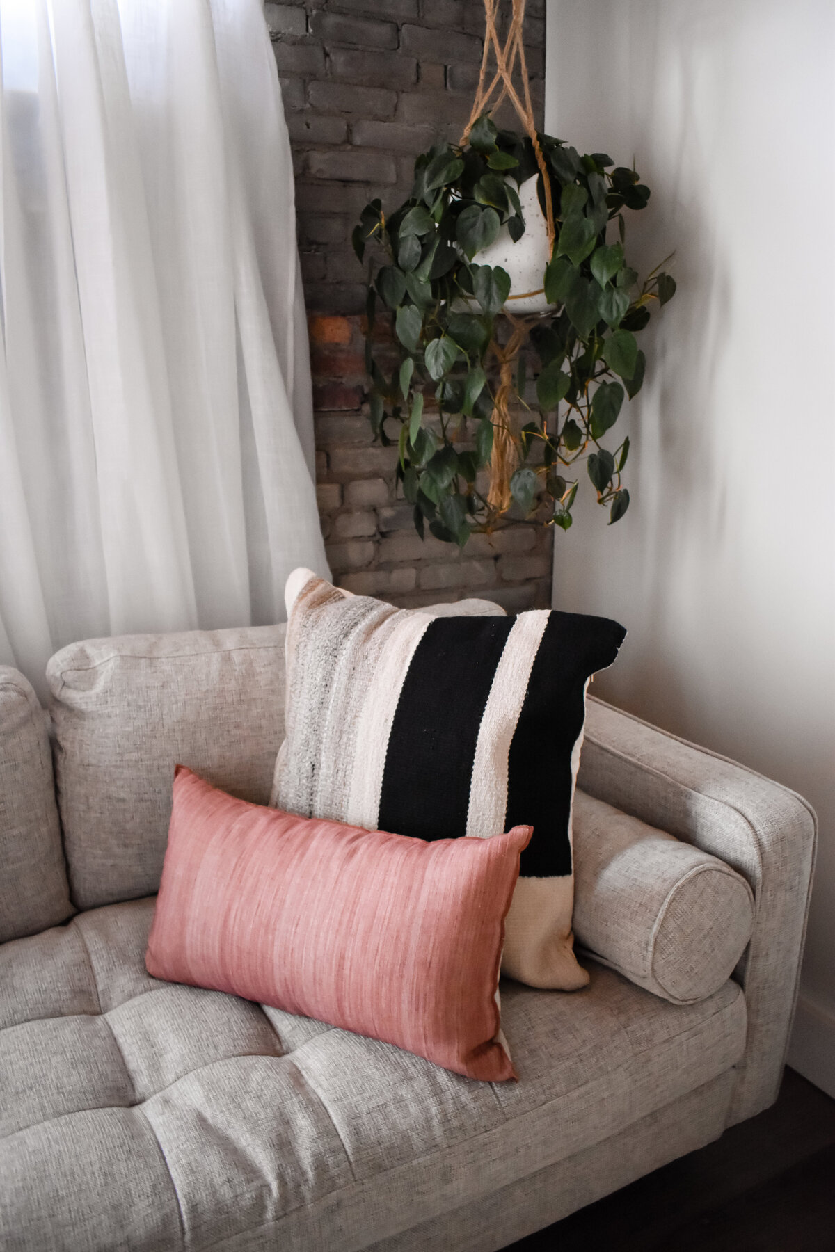 Pink and black and white pillows sit on a grey tufted couch