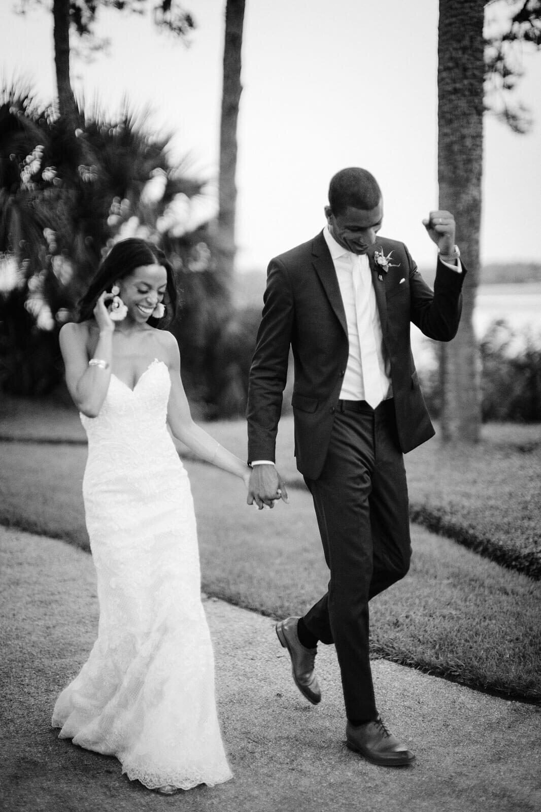 The bride and groom are happily walking outdoors in Montage at Palmetto Bluff. Destination Wedding Image by Jenny Fu Studio