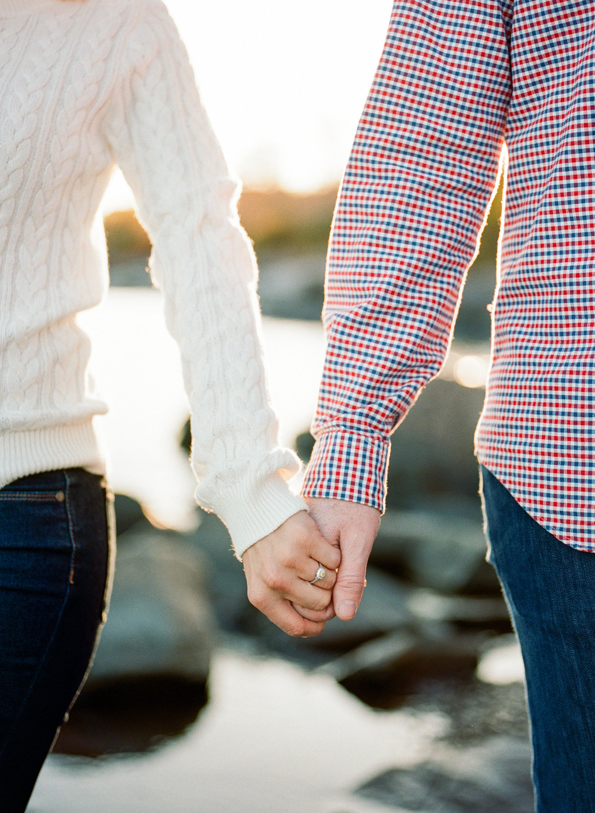 couple holds hands for engagement photography on north shore of minnesota