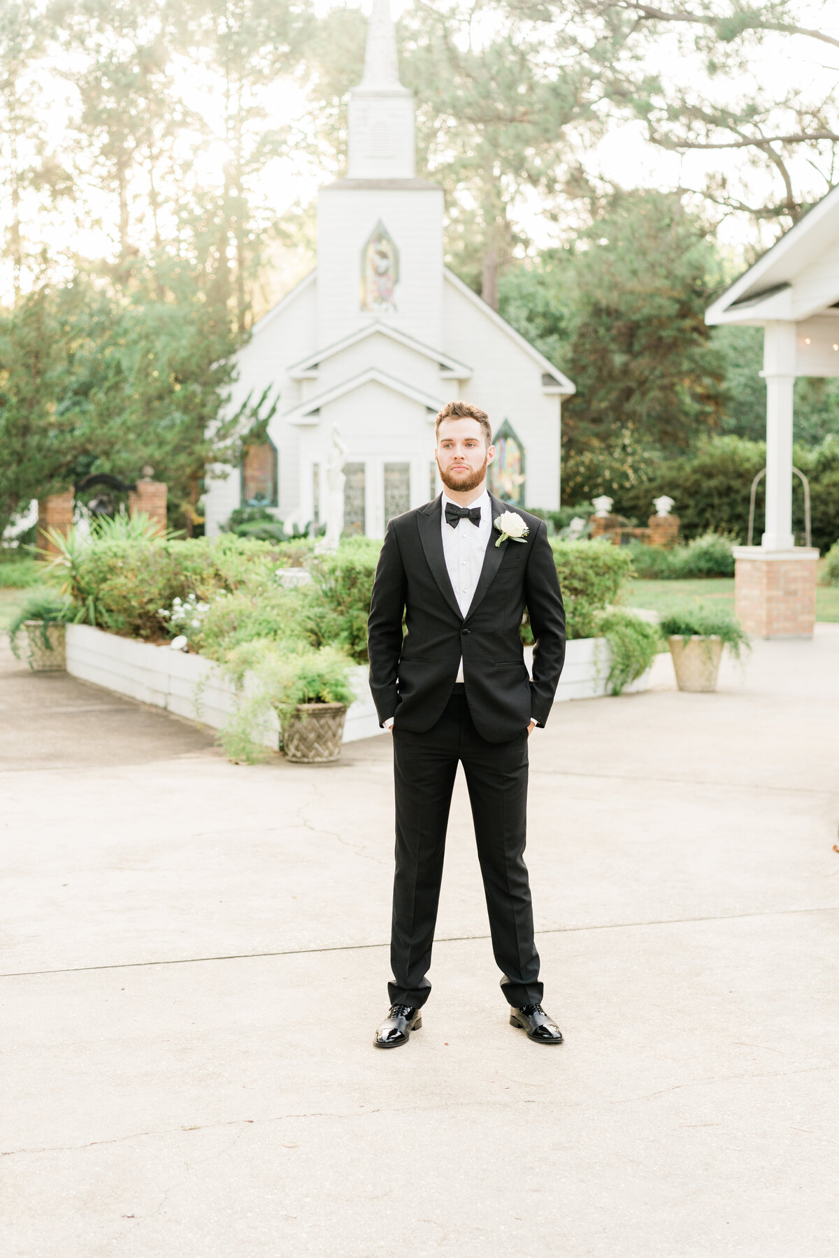 Groom in front of small white church in Alabama