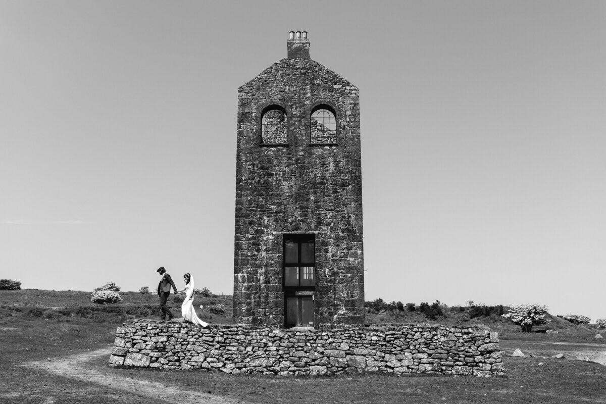 cornish wedding bride and groom climb tin mine wall in black and white