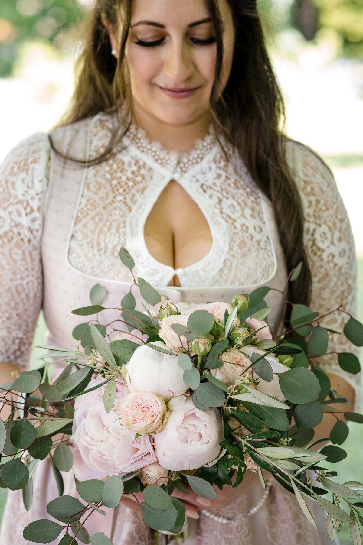 Braut in Tracht schaut auf ihren Brautstrauß Roseninsel Hochzeitsfotograf Starnberg