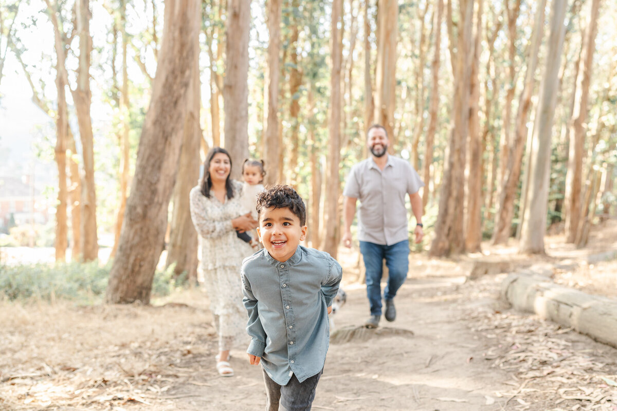 san francisco family photography at lovers lane in san francisco with 5-year-old boy leading the family through the trees
