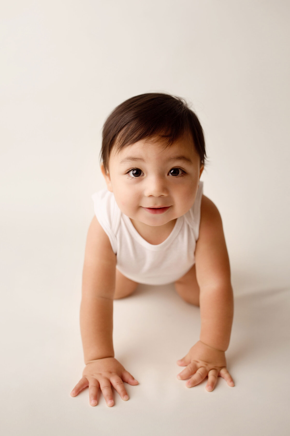 1 year old boy crawling on a white backdrop