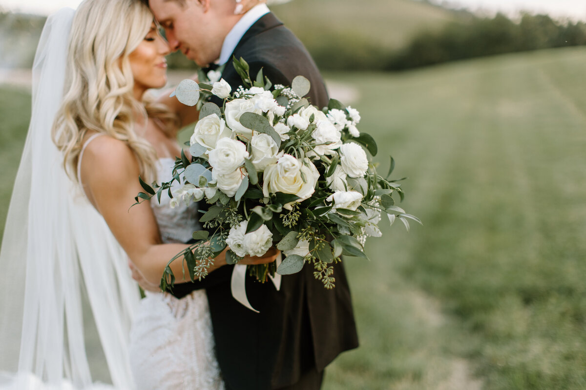 Romantic photo of bride and groom together featuring her bouquet