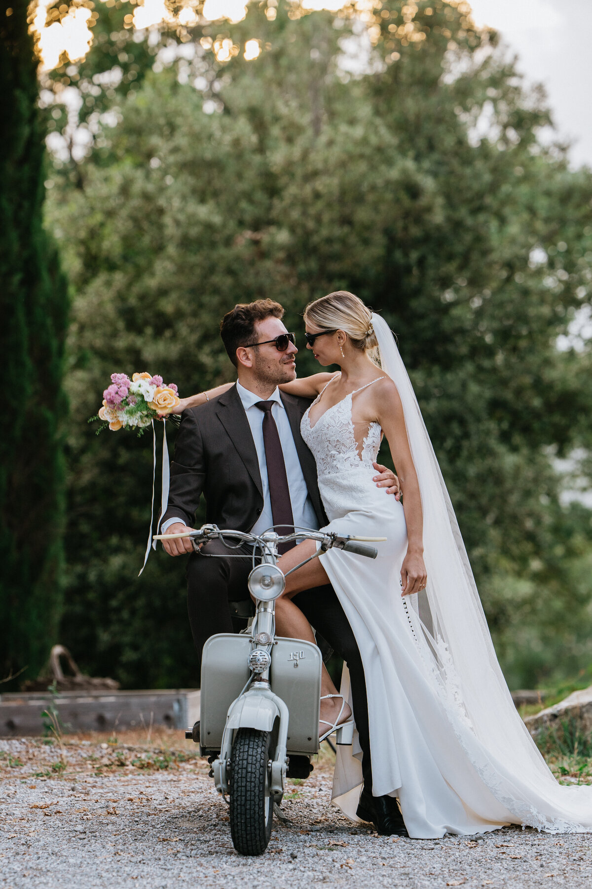 Wedding bride and groom with their old school Vespa in Tuscany