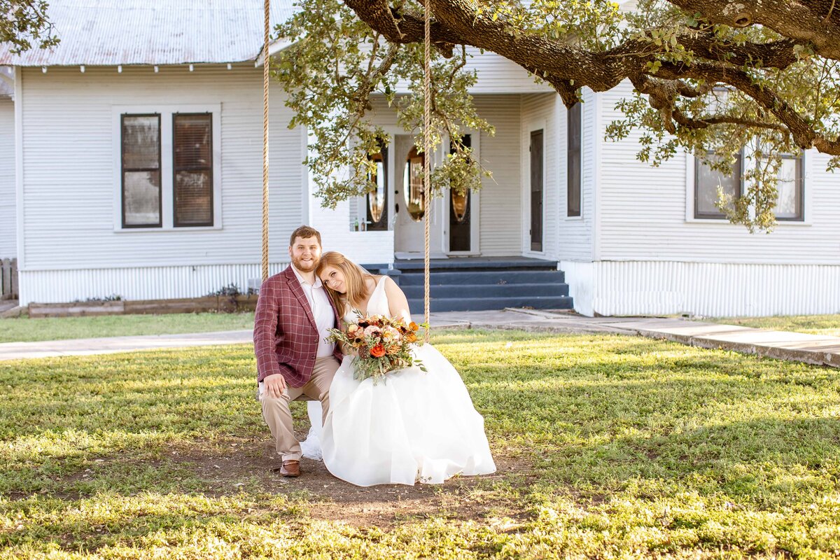 bride rests her head on her groom on swing at Allen Farmhaus in New Braunfels