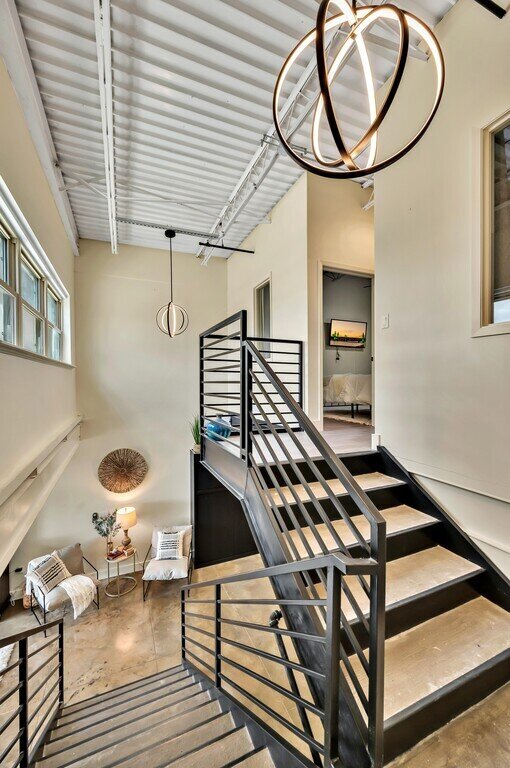 Beautiful staircase connecting main floor and upstairs bedrooms in this 2 bedroom, 2.5 bathroom luxury vacation rental loft condo for 8 guests with incredible downtown views, free parking, free wifi and professional decor in downtown Waco, TX.