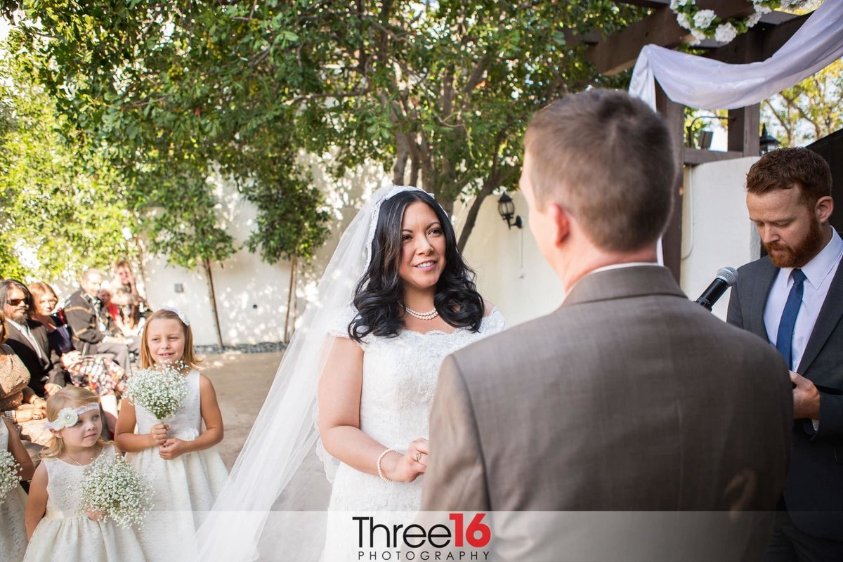 Bride smiles at her Groom as he takes repeats his vows