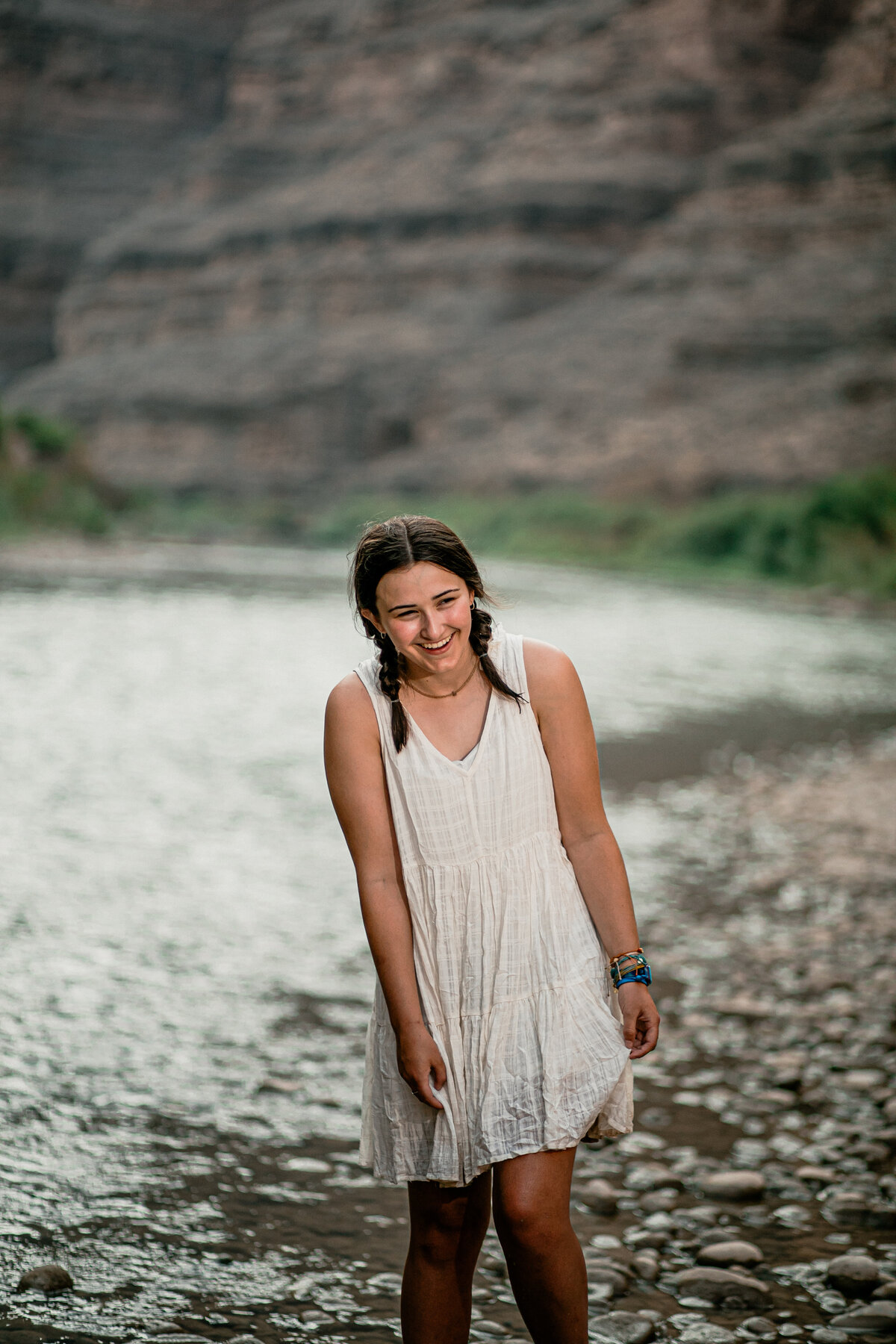 a girl laughs while standing in the san juan river