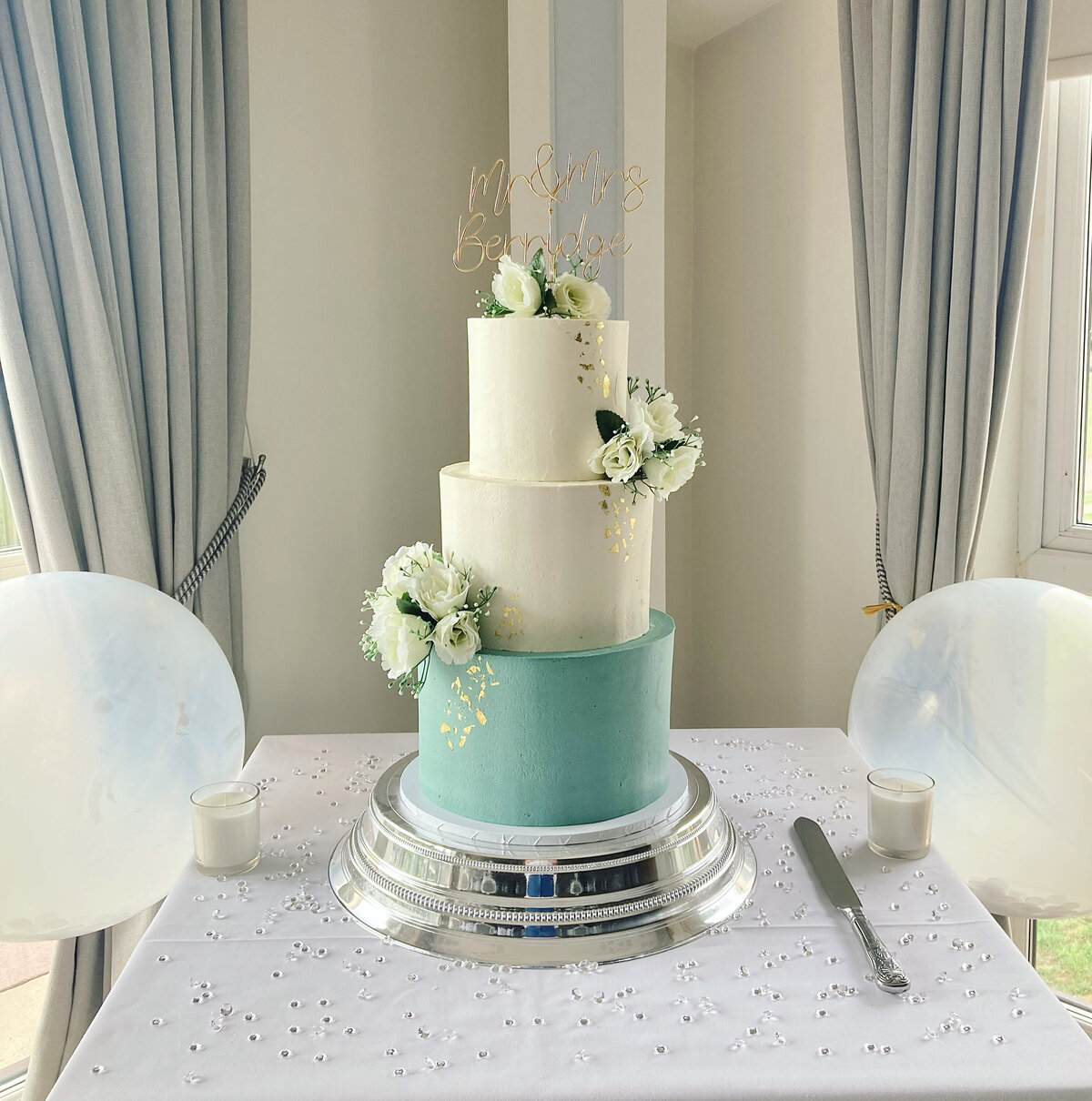 White and sage green wedding cake with silk flowers and gold leaf