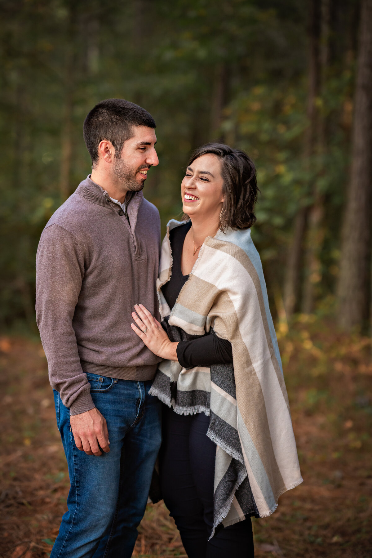 A husband and wife are laughing as they pose at their photoshoot with Ashley Zohil Photography.