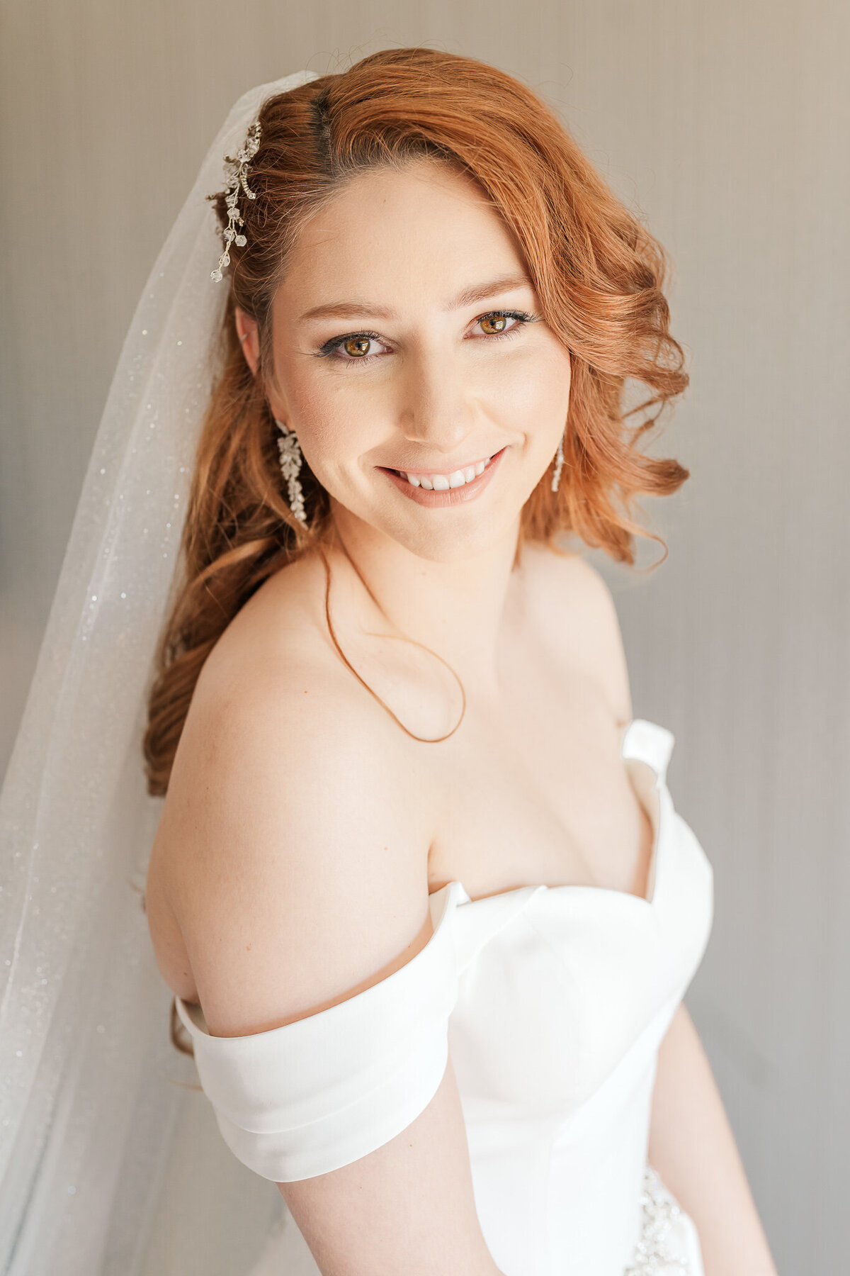 A smiling redheaded bride on her wedding day getting bridal portraits by Raleigh wedding photographer, JoLynn Photography