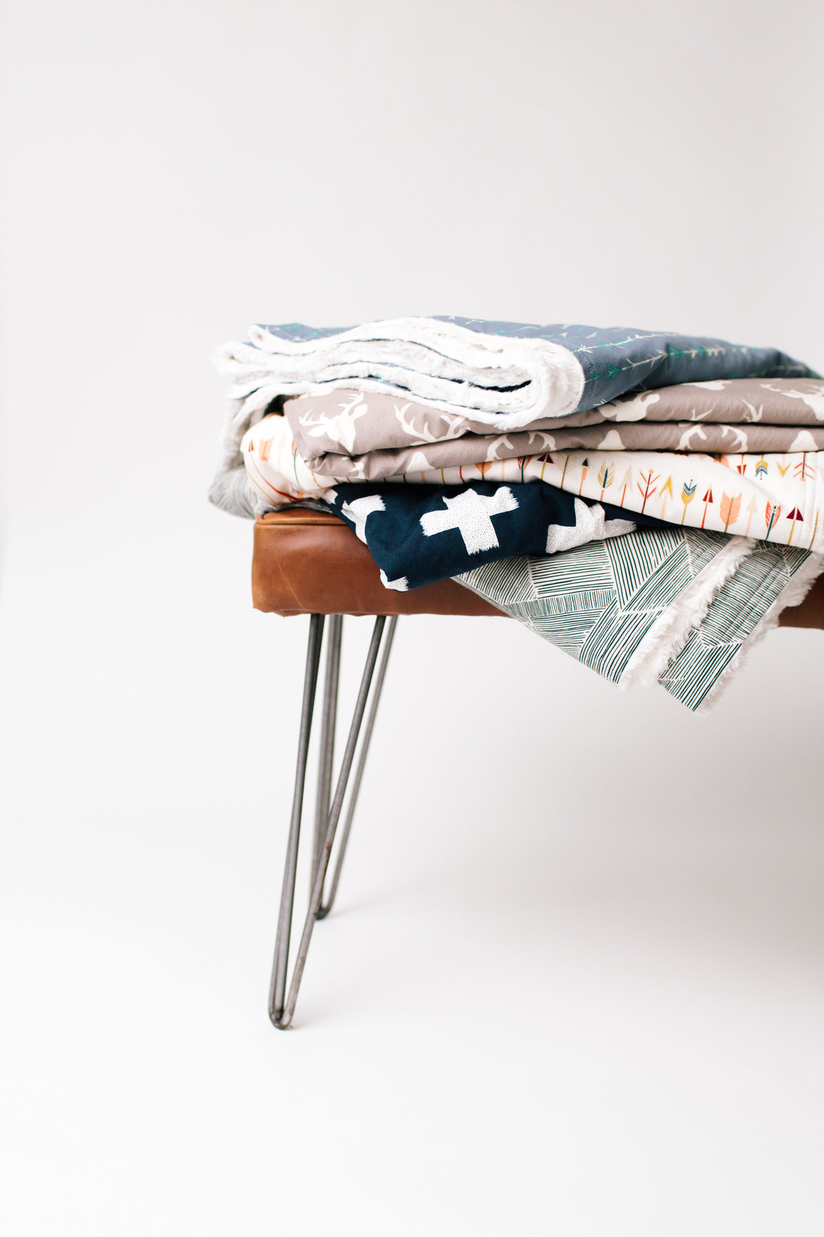 blankets stacked on leather bench with white background