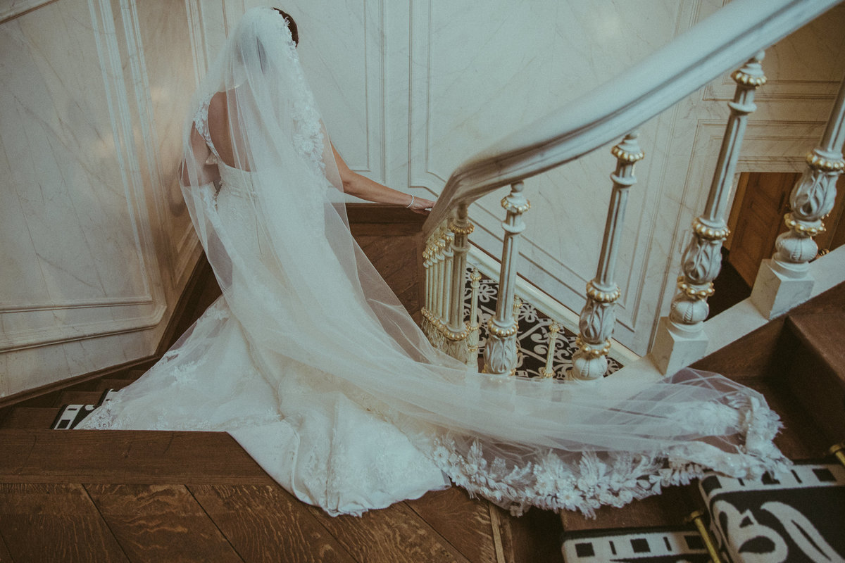 Bruid loopt trap af. Bride descending stairs. Made bij FOTOZEE