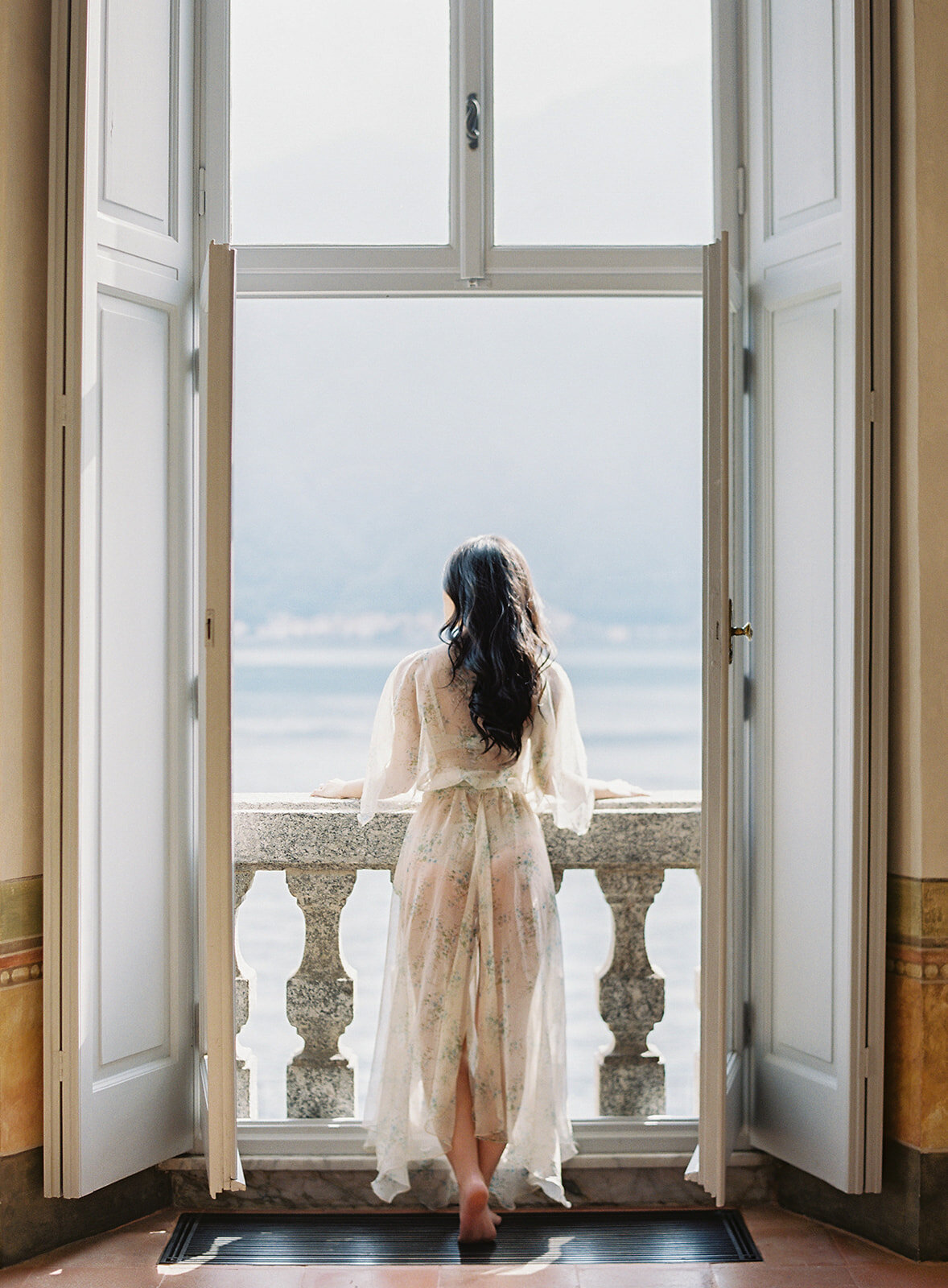 bride looking out window at lake como