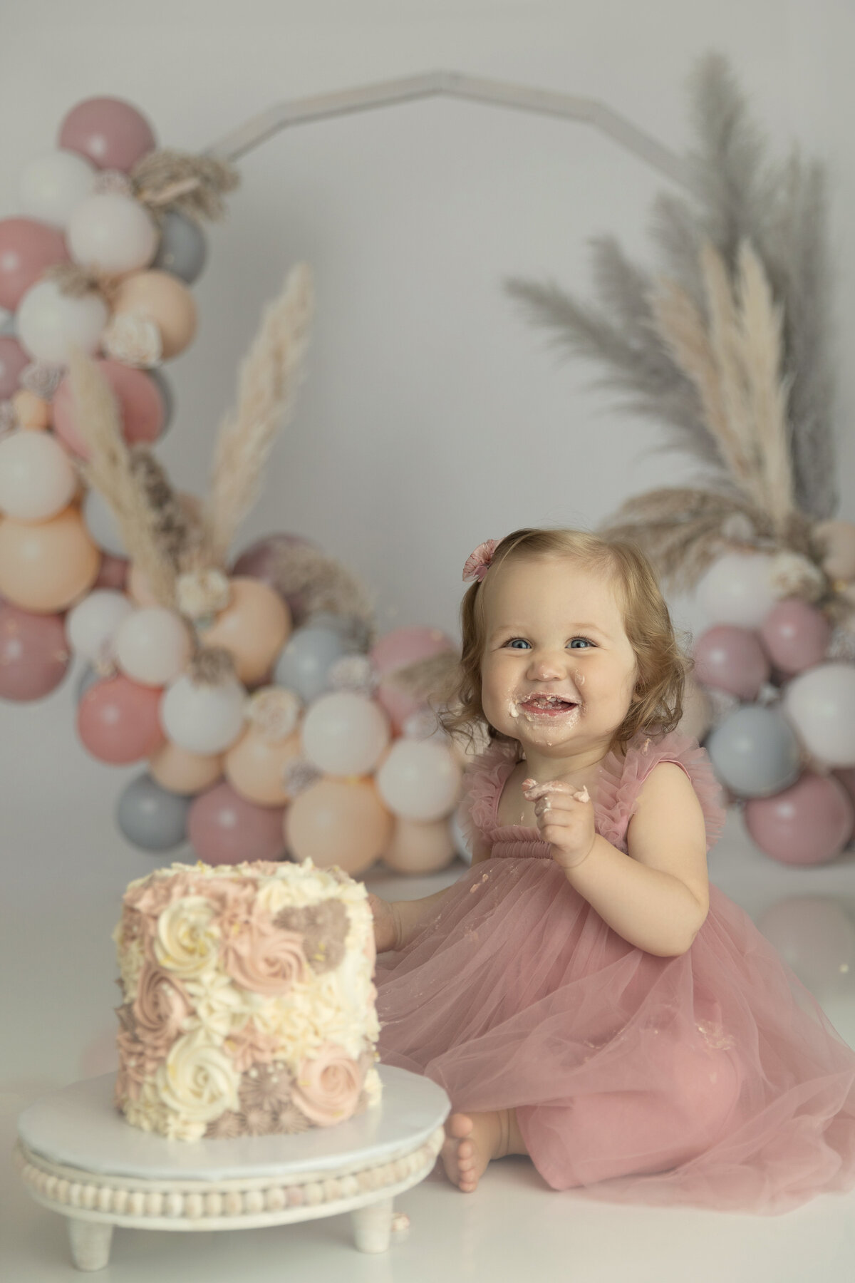 A toddler girl happily eats a flower designed cake for a New Jersey Milestone Photographer
