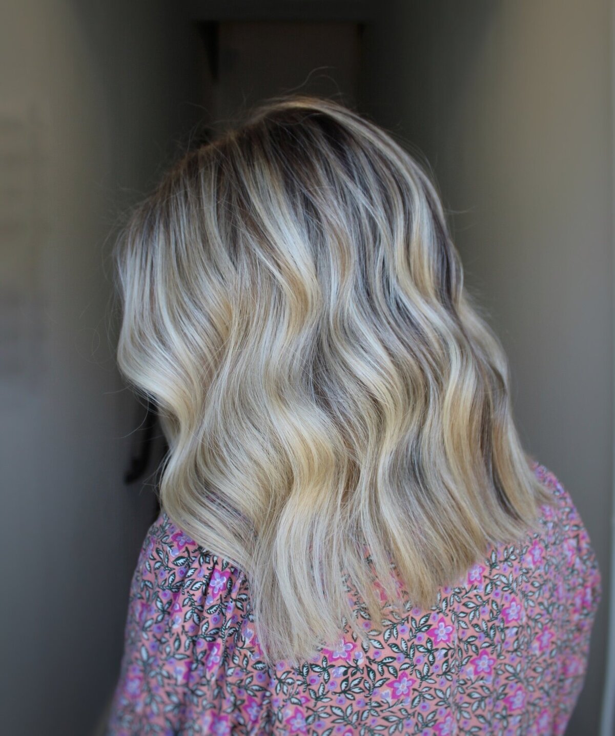 Rear view of wavy blonde highlighted hair with dark roots