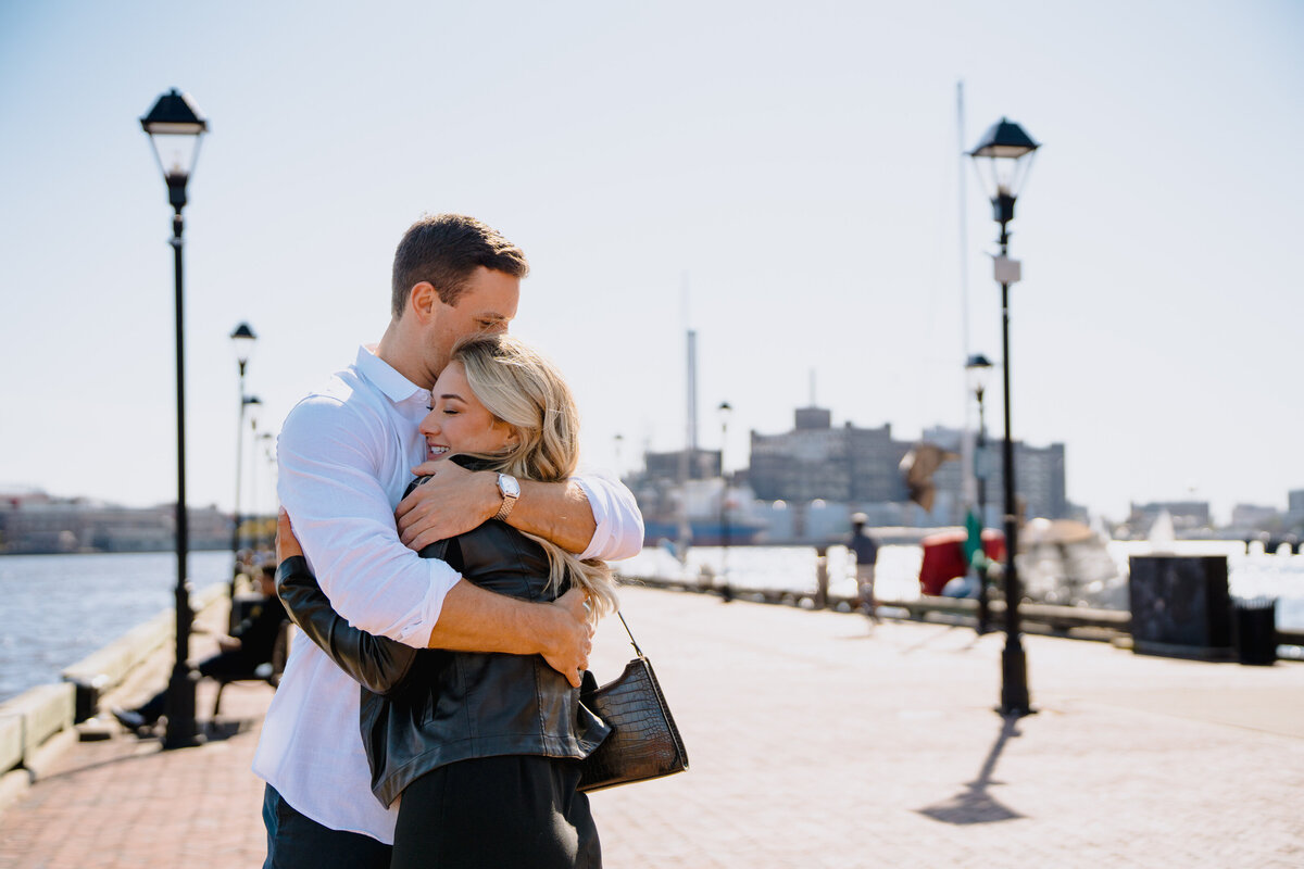 A couple hugging while standing on a pier.